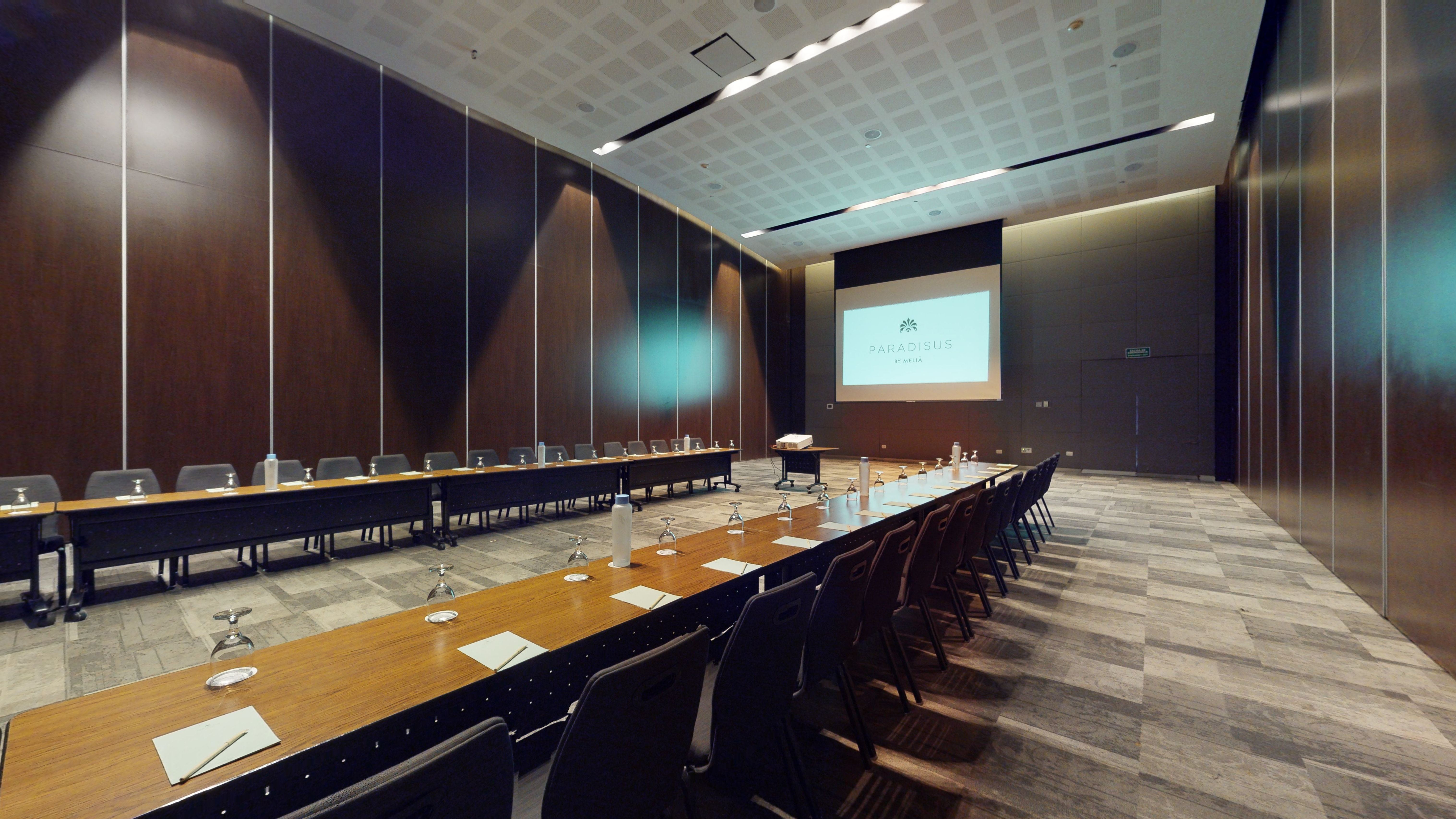 Spacious conference room with meeting setup and Paradisus by Meliá screen.