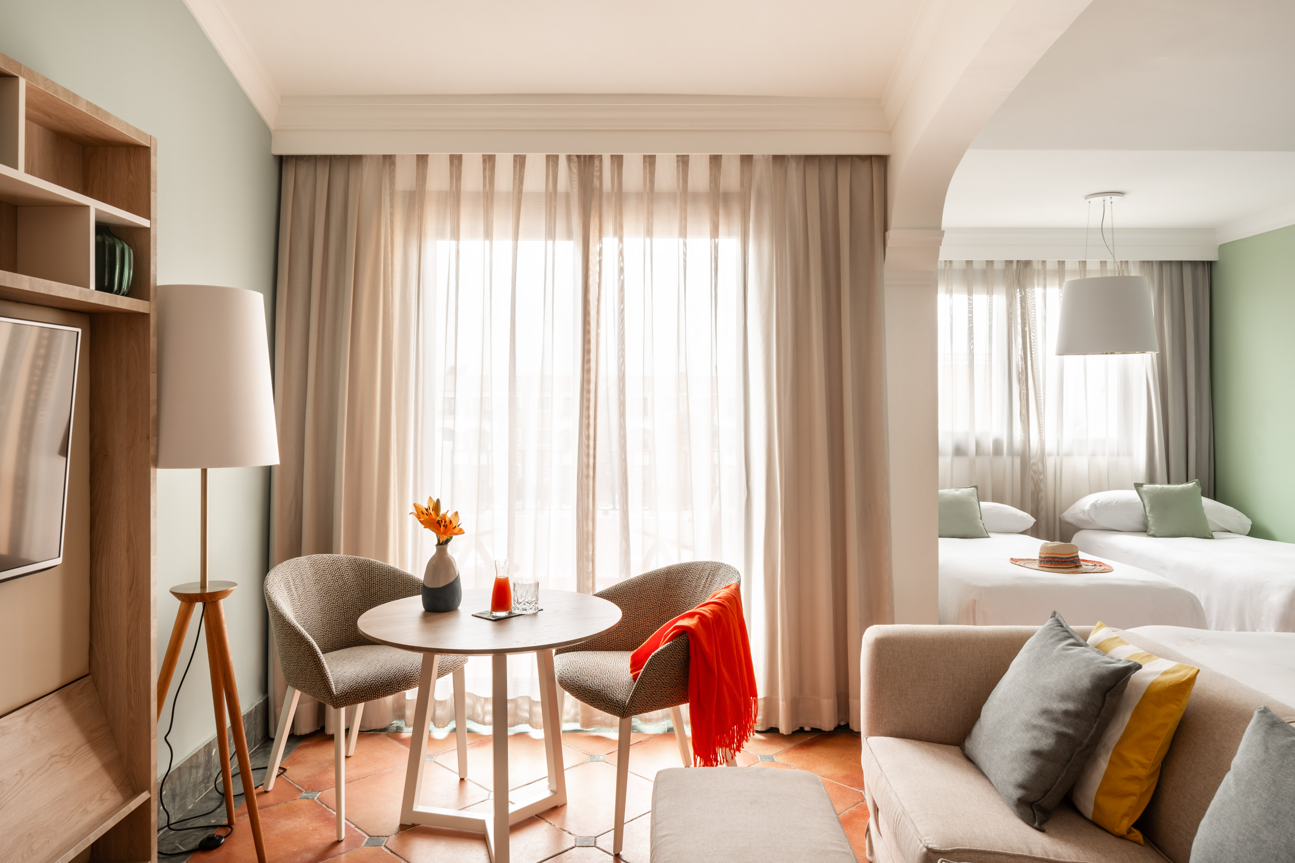 Hotel suite living area with table, chairs, plus bedroom with two twin beds.