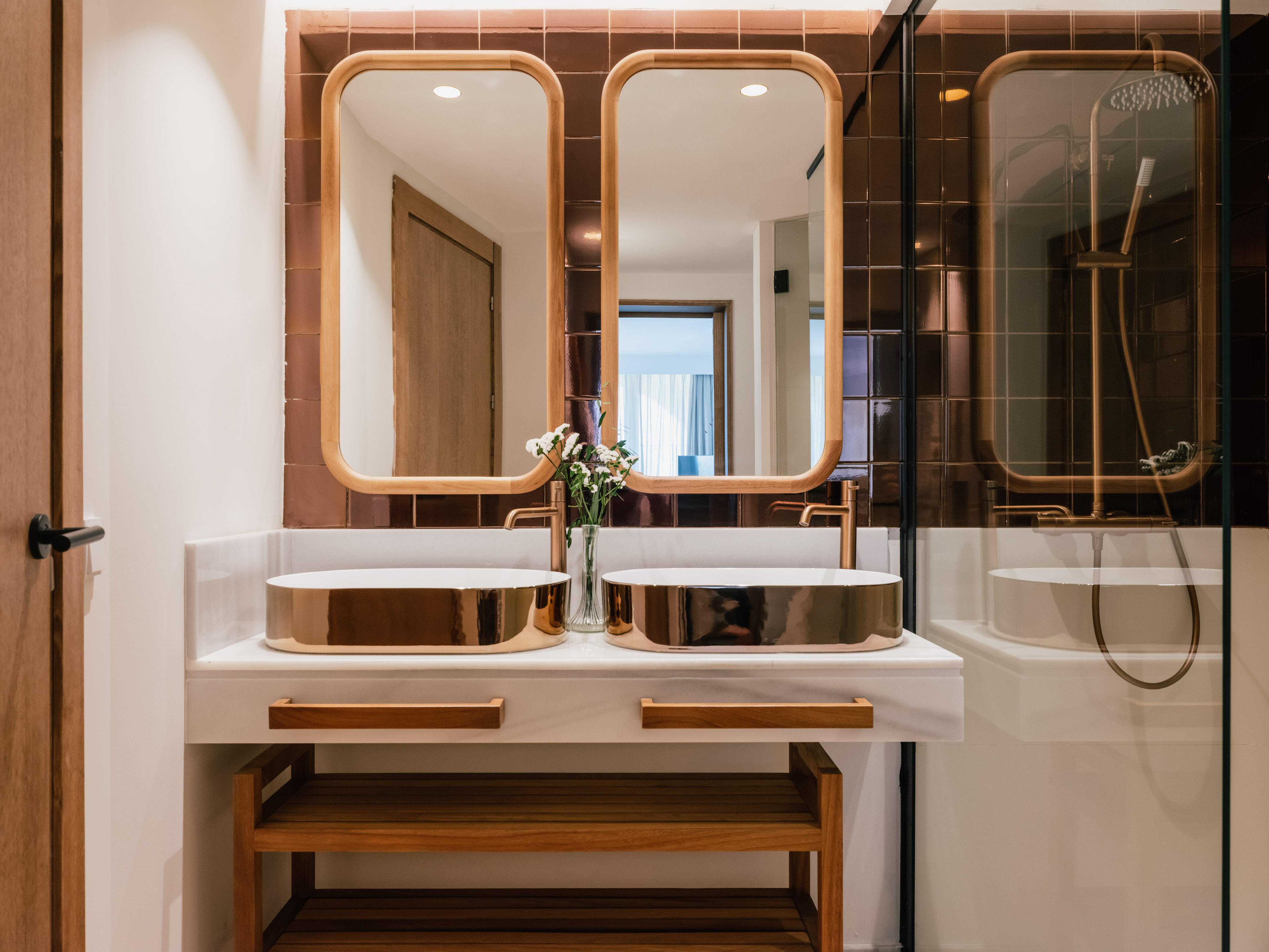 Modern bathroom with two copper sinks, marble counter, wood framed mirrors.