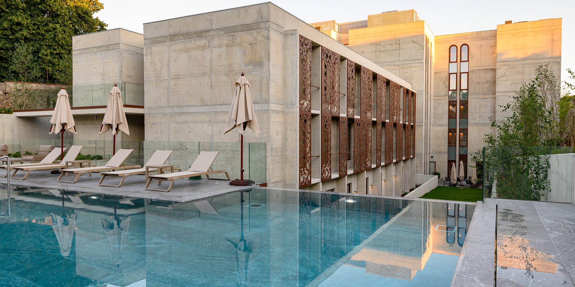 a pool with chairs and umbrellas in front of a building