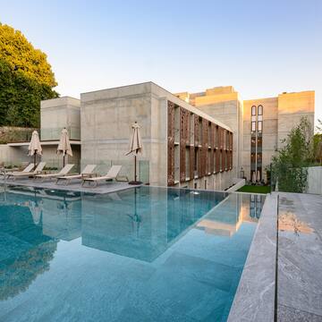 a pool with chairs and umbrellas in front of a building