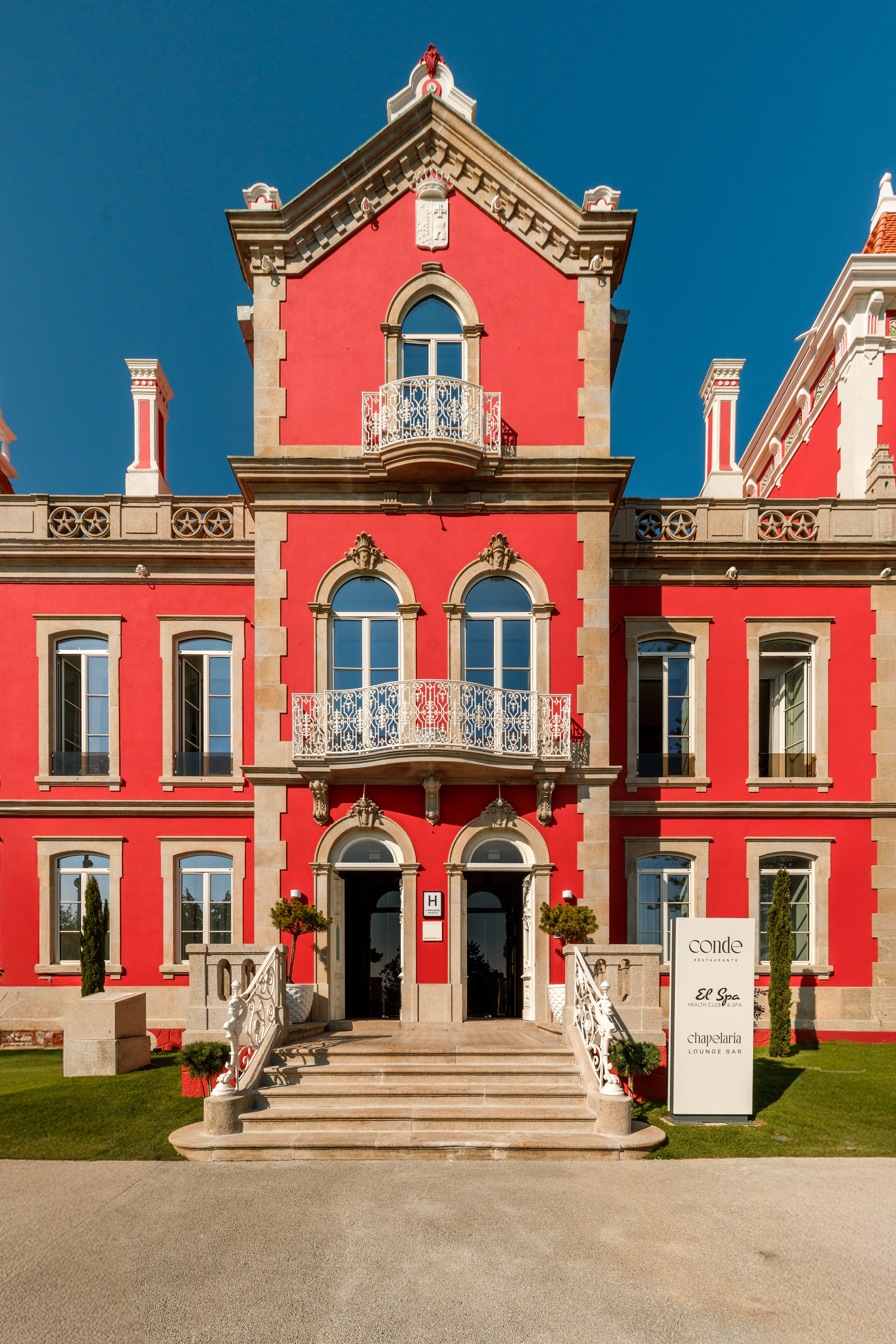 Red hotel with ornate balconies, grand entrance, and spa & restaurant signage.