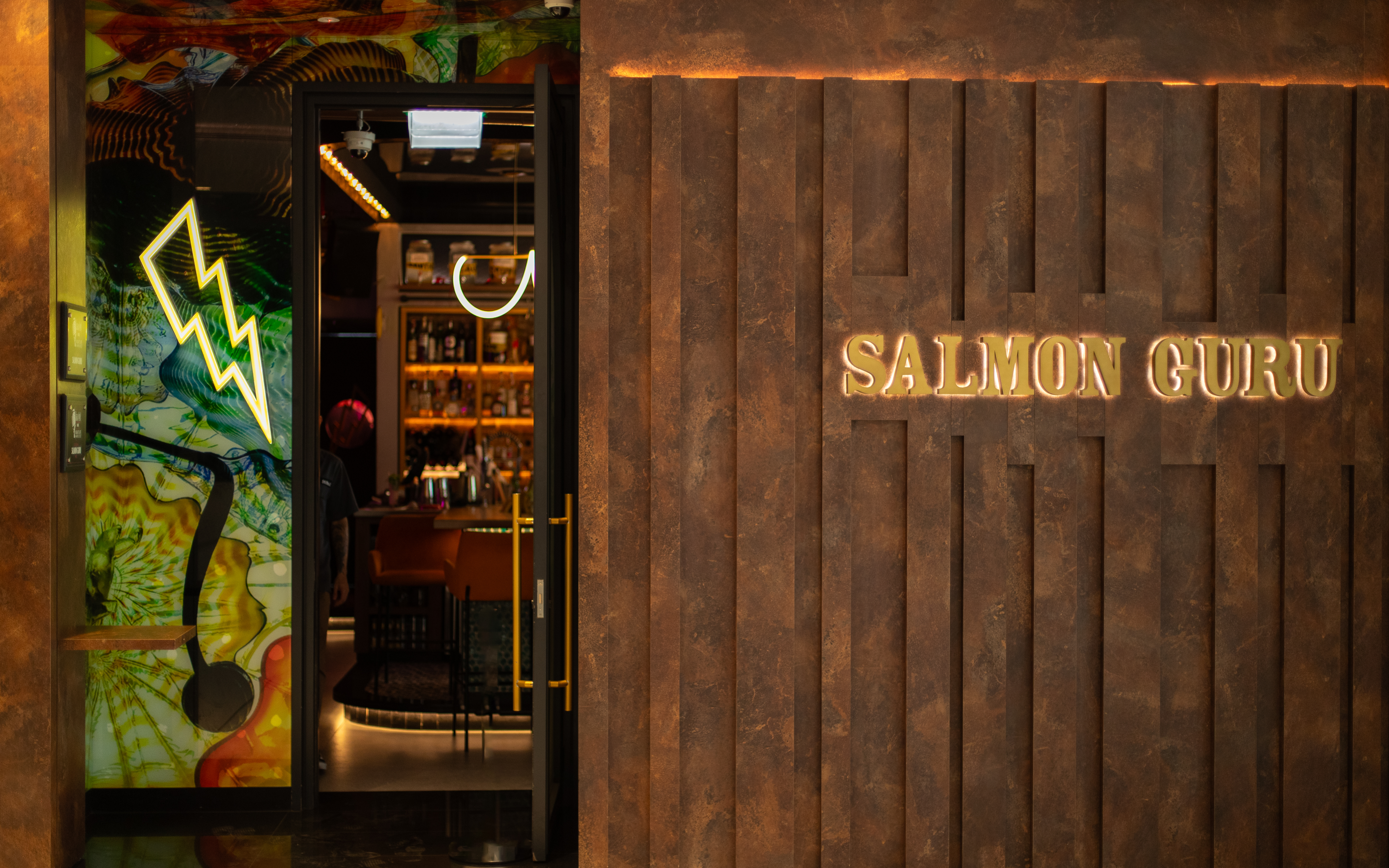 Modern Salmon Guru bar entrance with illuminated sign and neon lightning bolt.