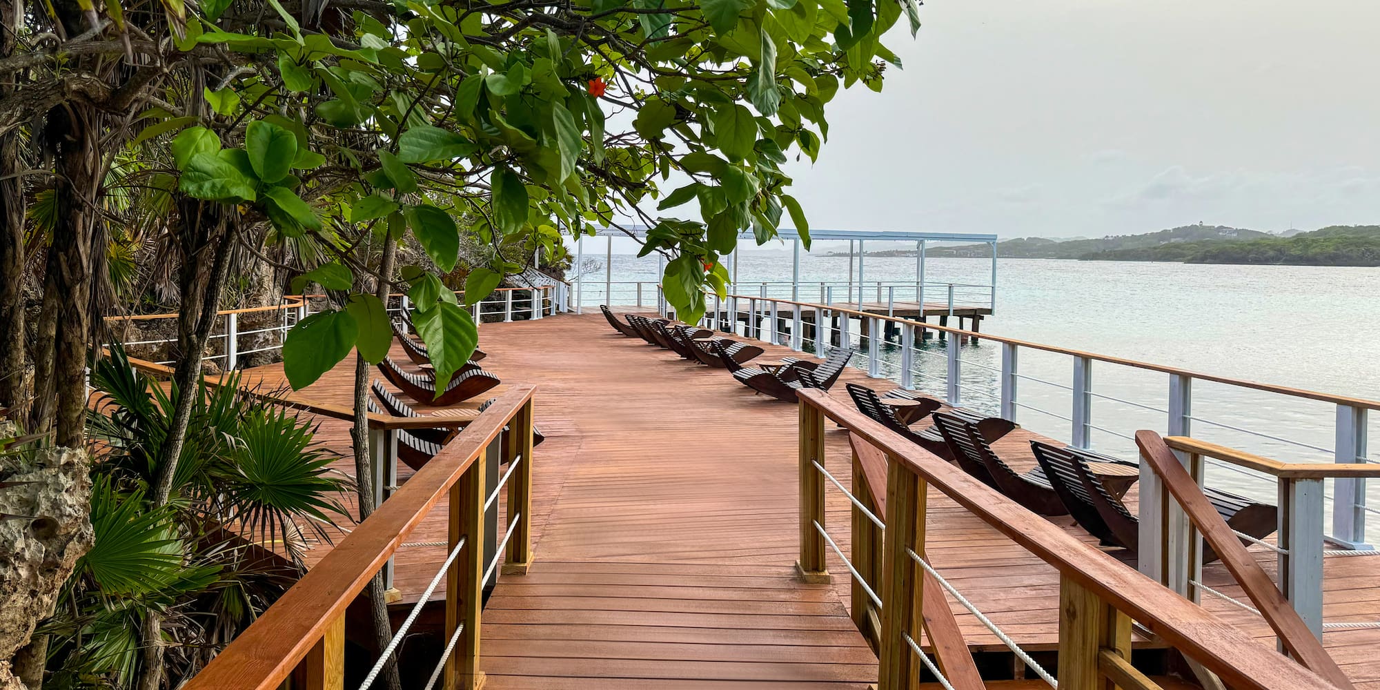 a wooden walkway with chairs and railings on a beach