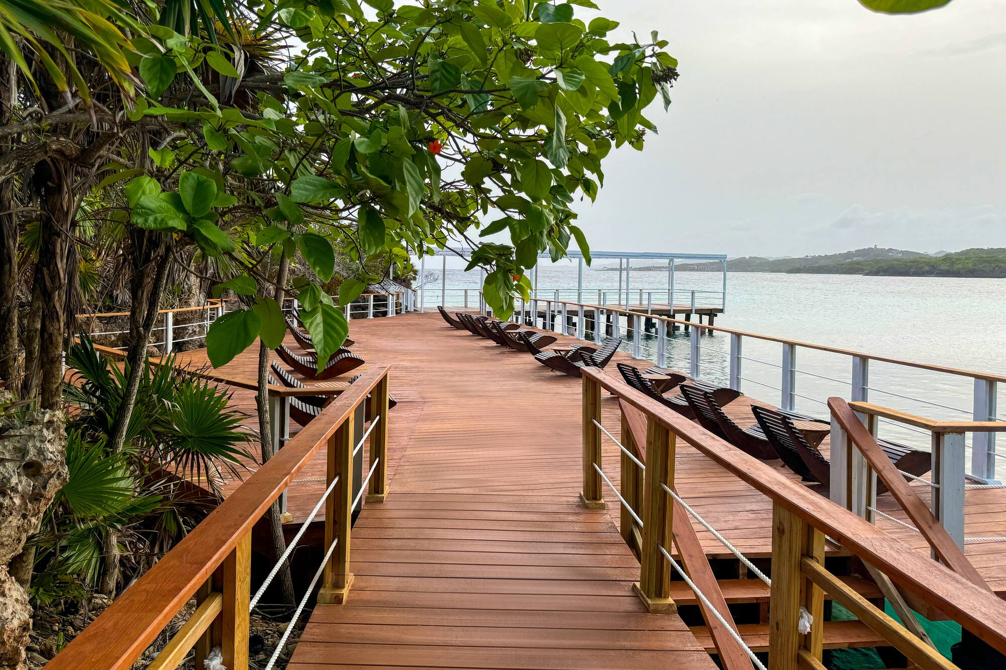 a wooden walkway with chairs and railings on a beach