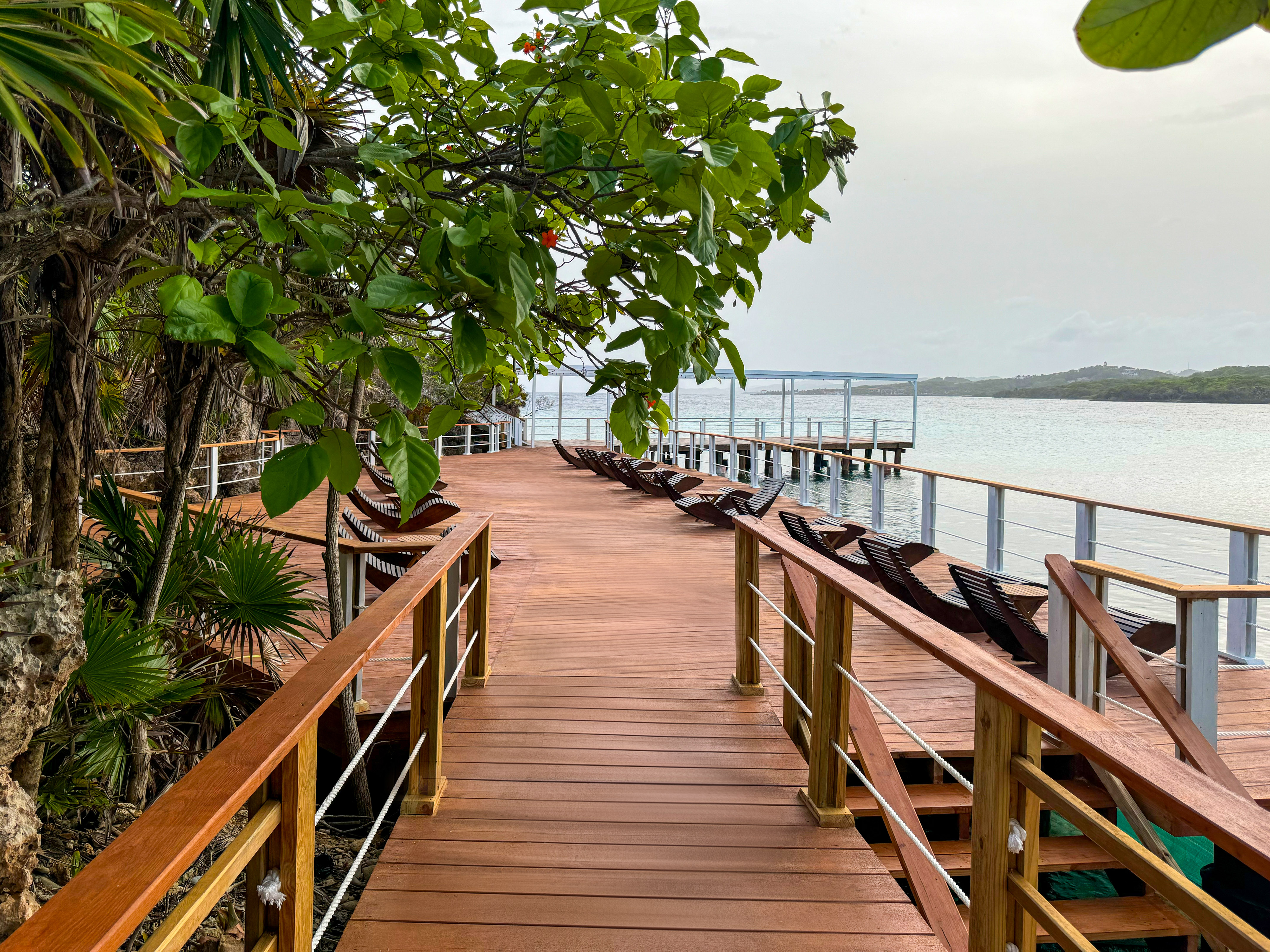 a wooden walkway with chairs and railings on a beach