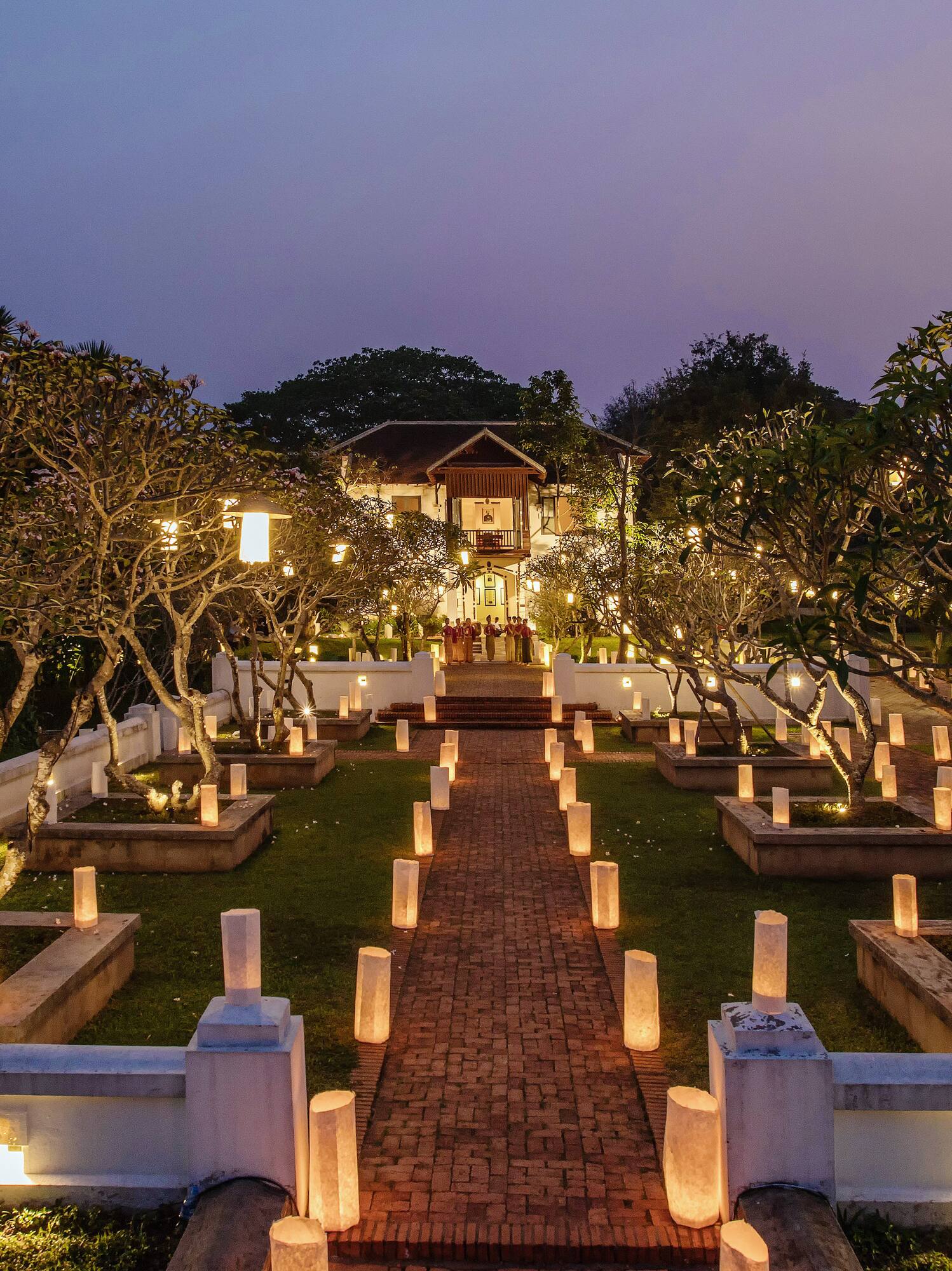 a brick path with trees and lights on it