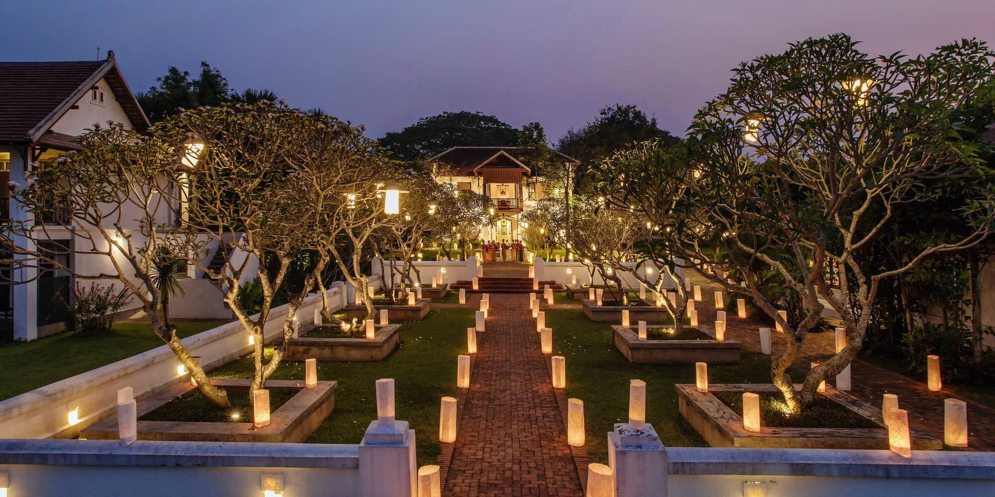 a brick path with trees and lights on it