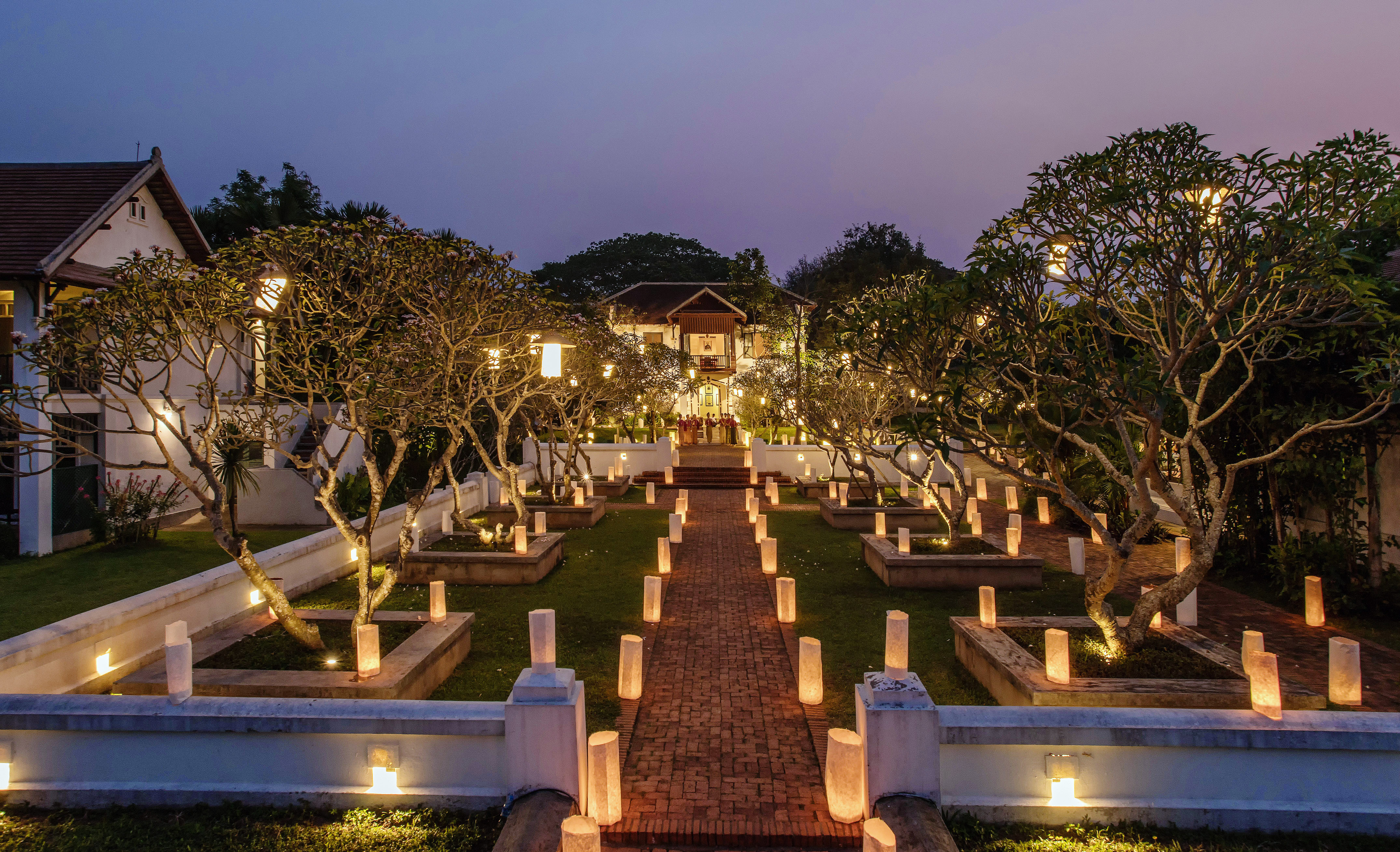 a brick path with trees and lights on it