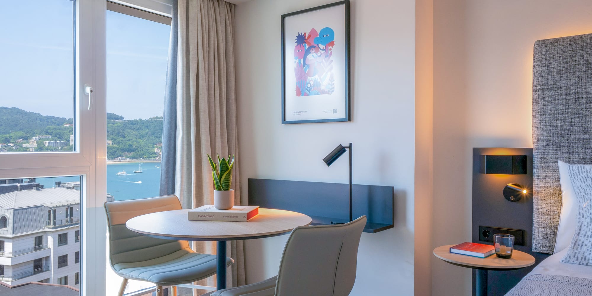 Habitación de hotel con vistas a la bahía, decoración moderna y mesa.