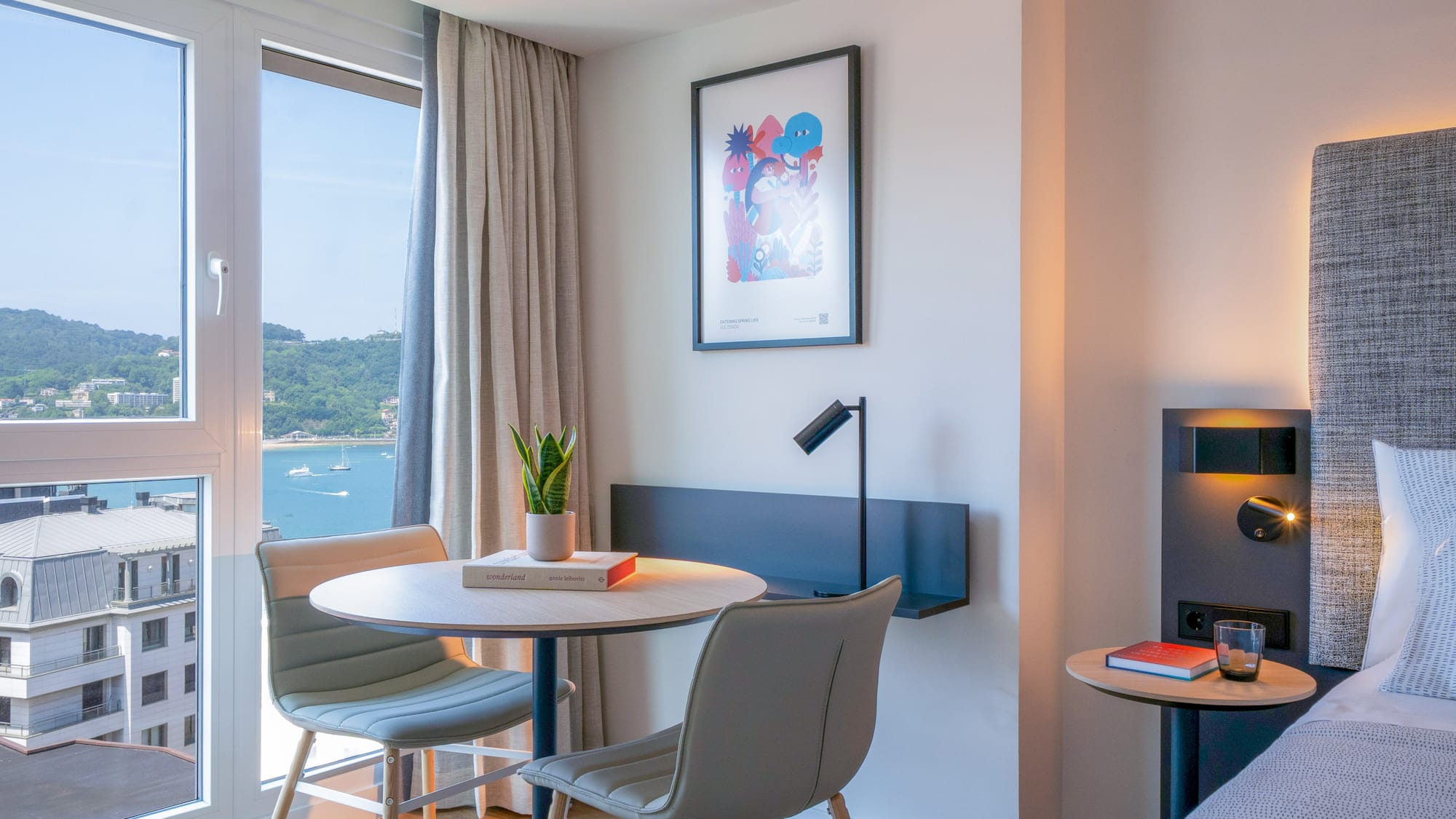 Habitación de hotel con vistas a la bahía, decoración moderna y mesa.