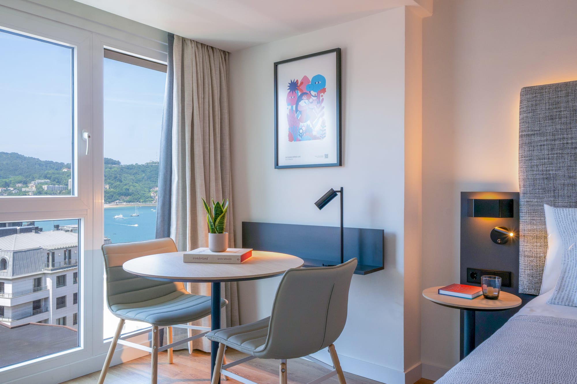 Habitación de hotel con vistas a la bahía, decoración moderna y mesa.