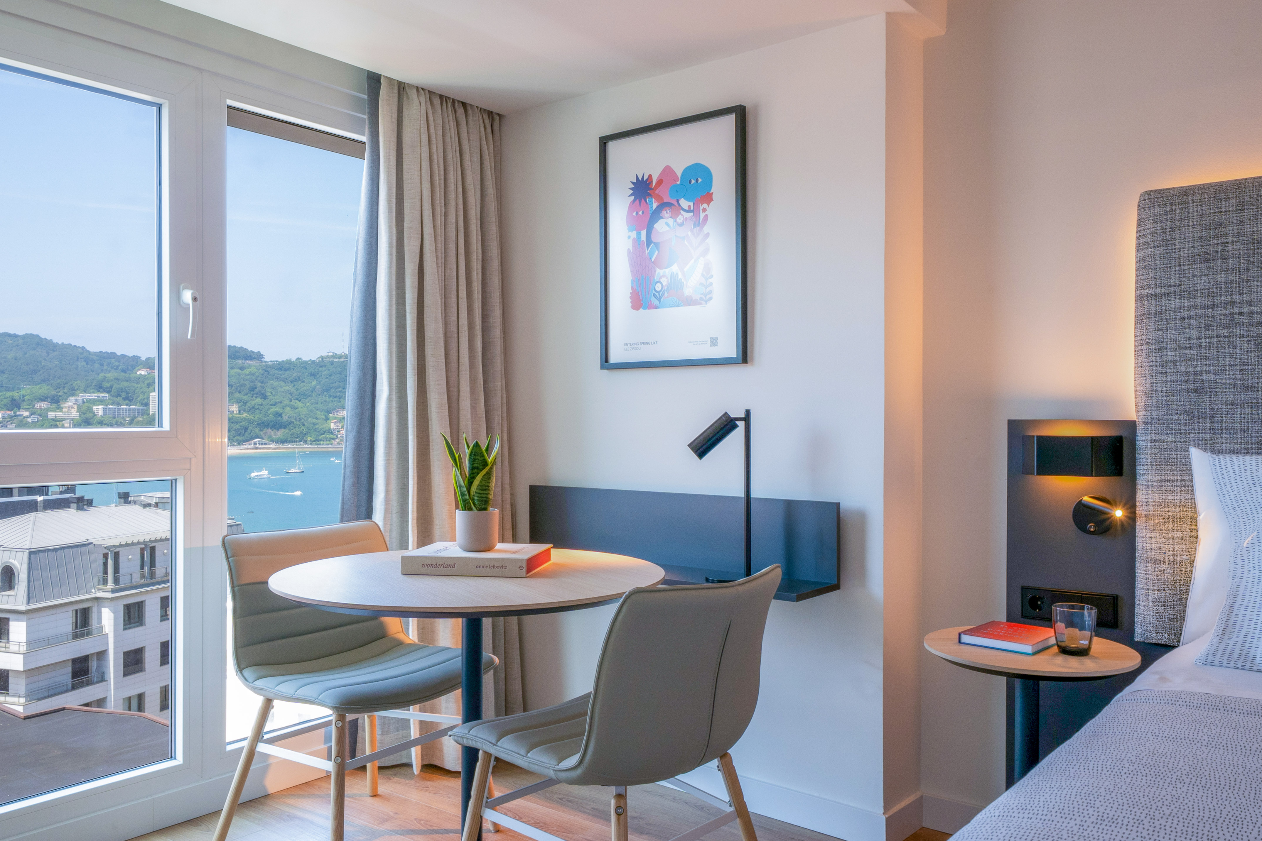 Habitación de hotel con vistas a la bahía, decoración moderna y mesa.