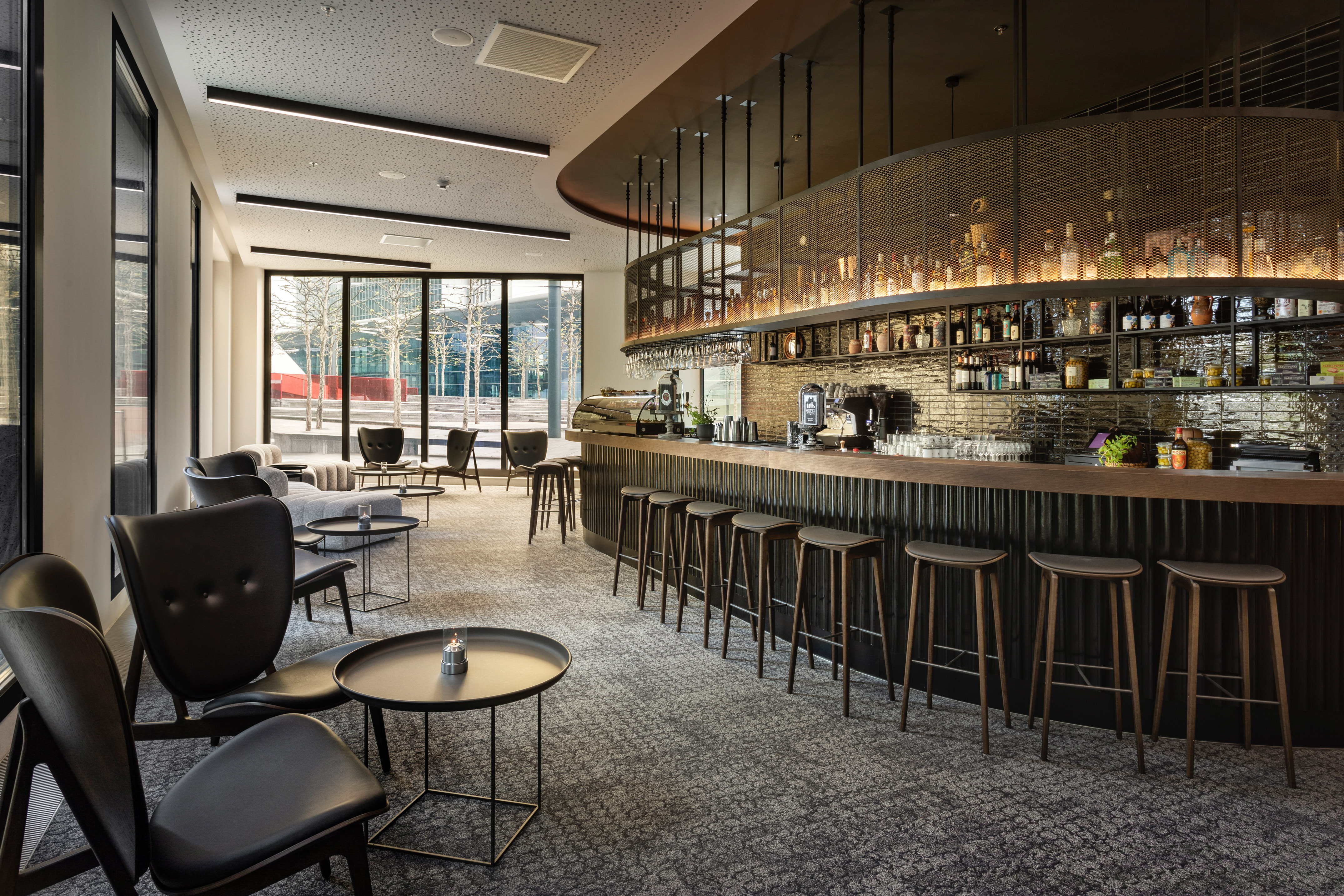 Modern hotel bar lounge with dark counter, bar stools, and comfortable seating.