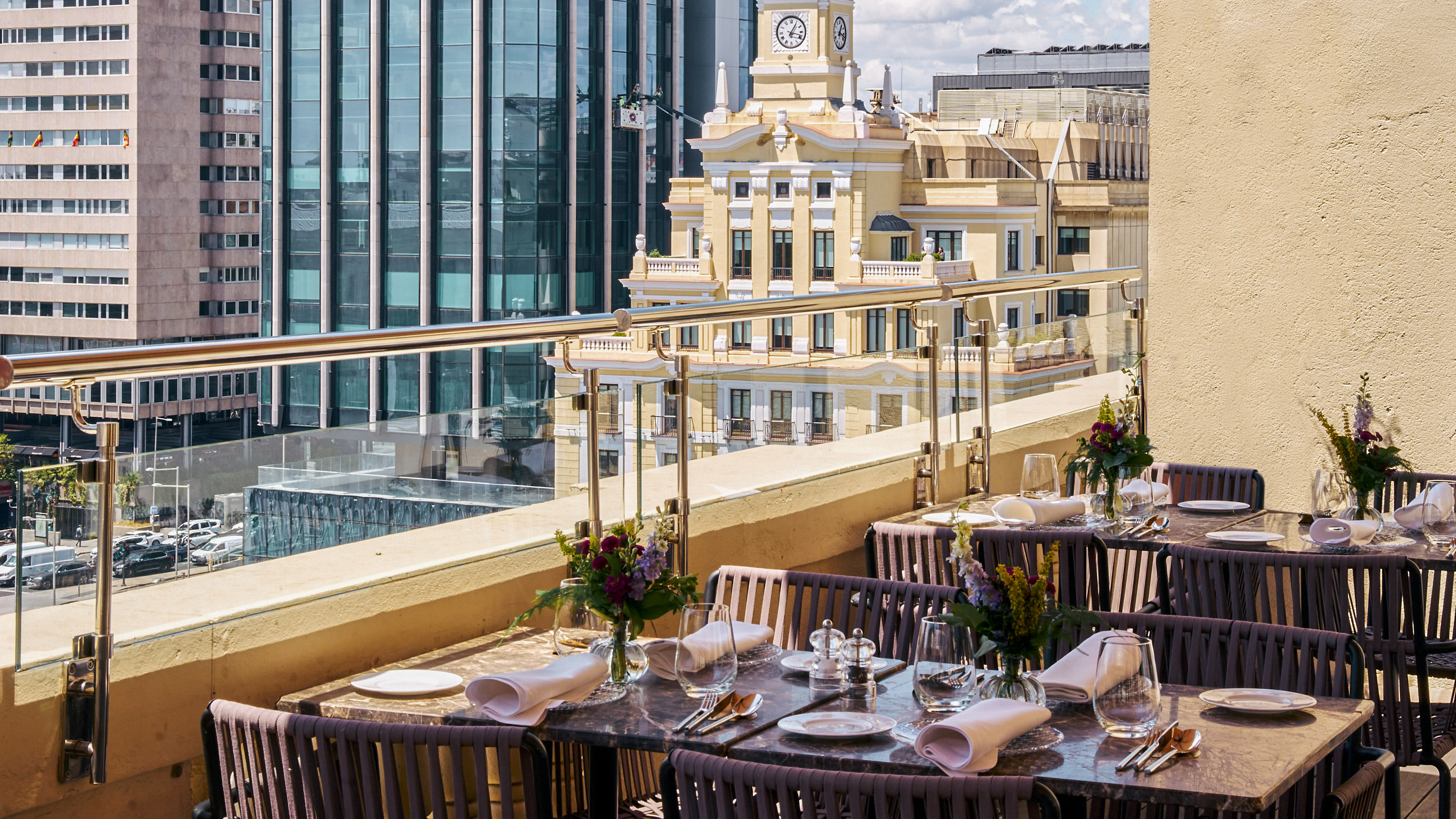 Rooftop dining terrace with set tables, city view, and a classic clock tower.