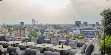 a patio with tables and chairs and a city view
