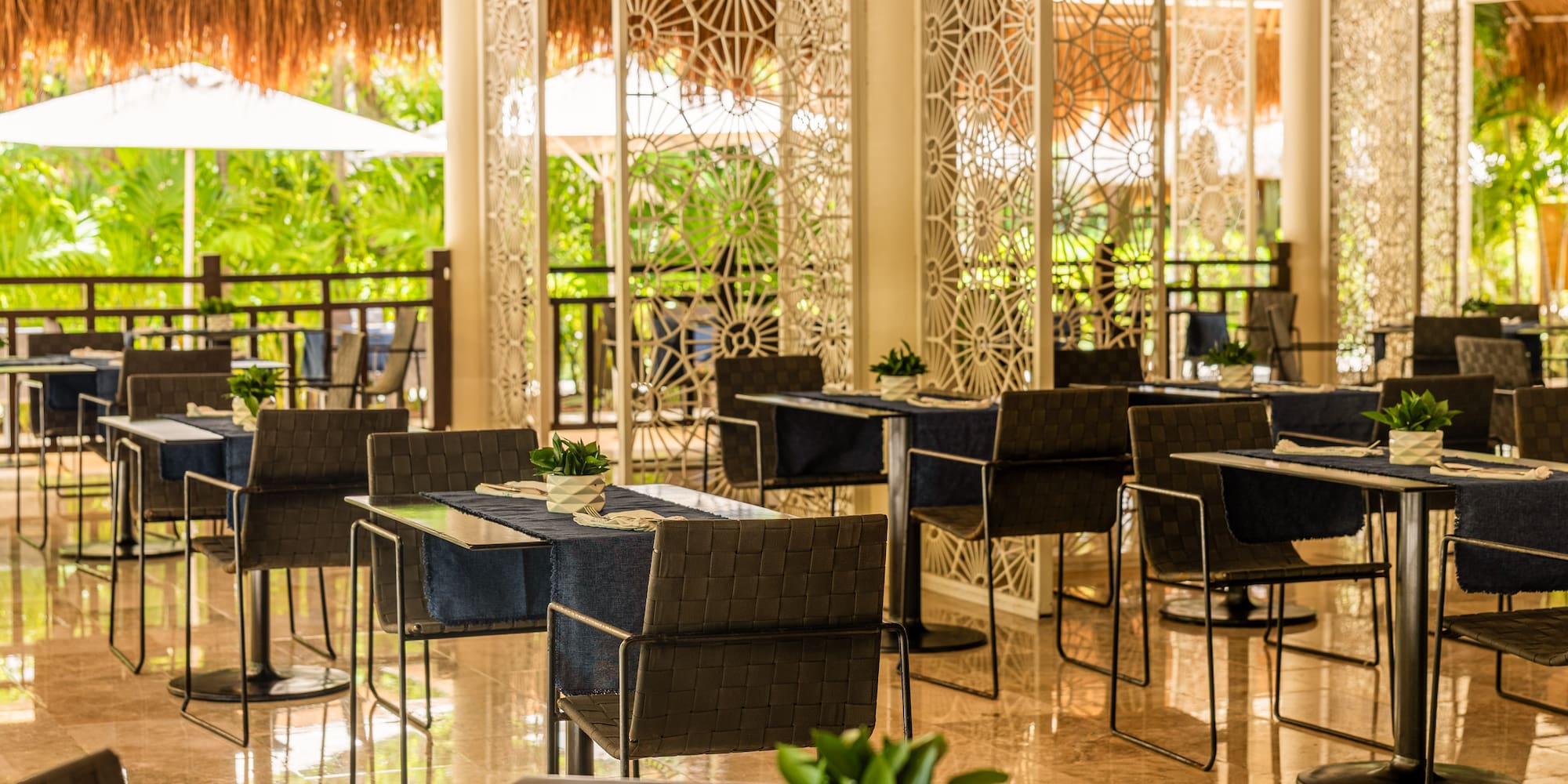 Tropical restaurant with modern tables, chairs, and lush outdoor views.