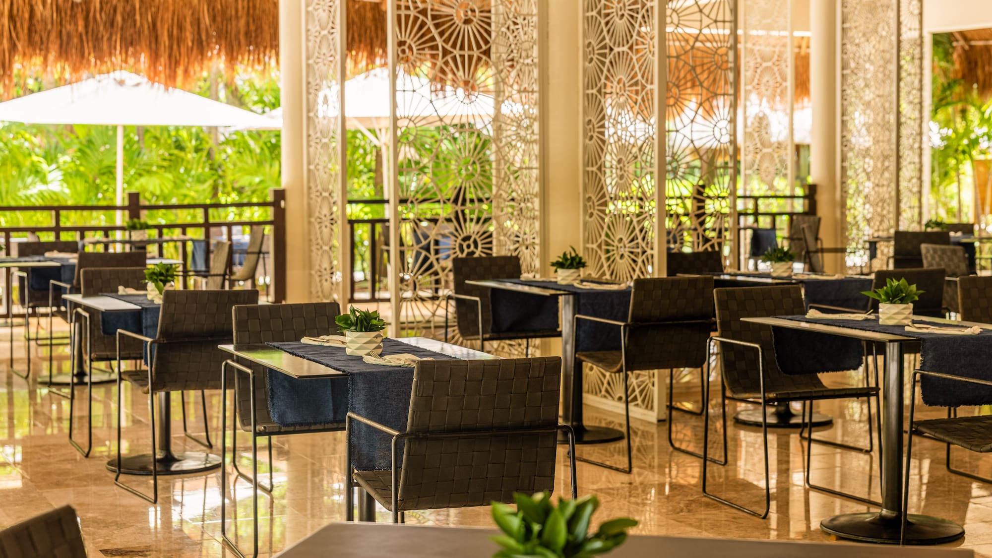Tropical restaurant with modern tables, chairs, and lush outdoor views.