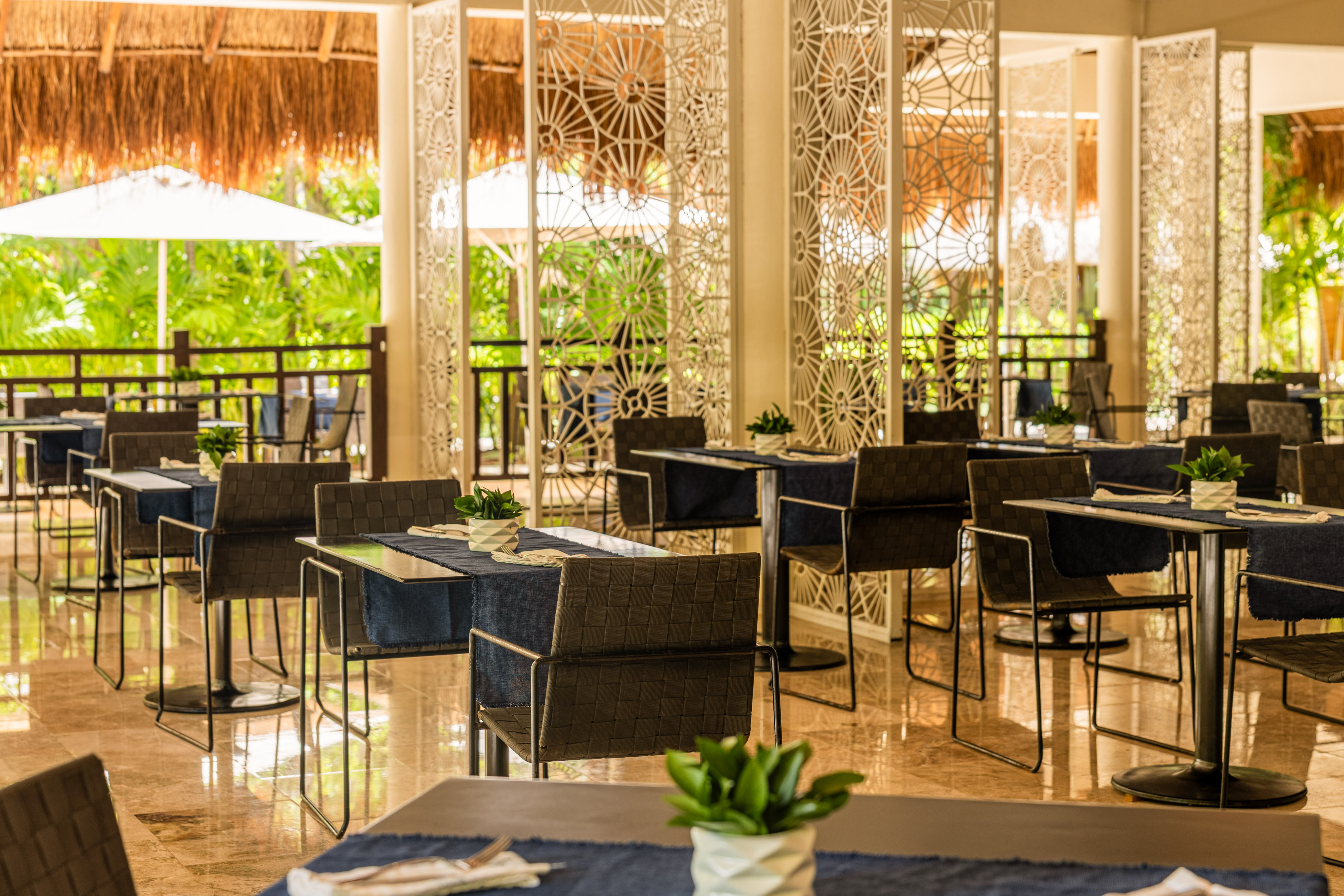 Tropical restaurant with modern tables, chairs, and lush outdoor views.