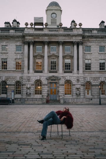 a person sitting on a chair in front of a building