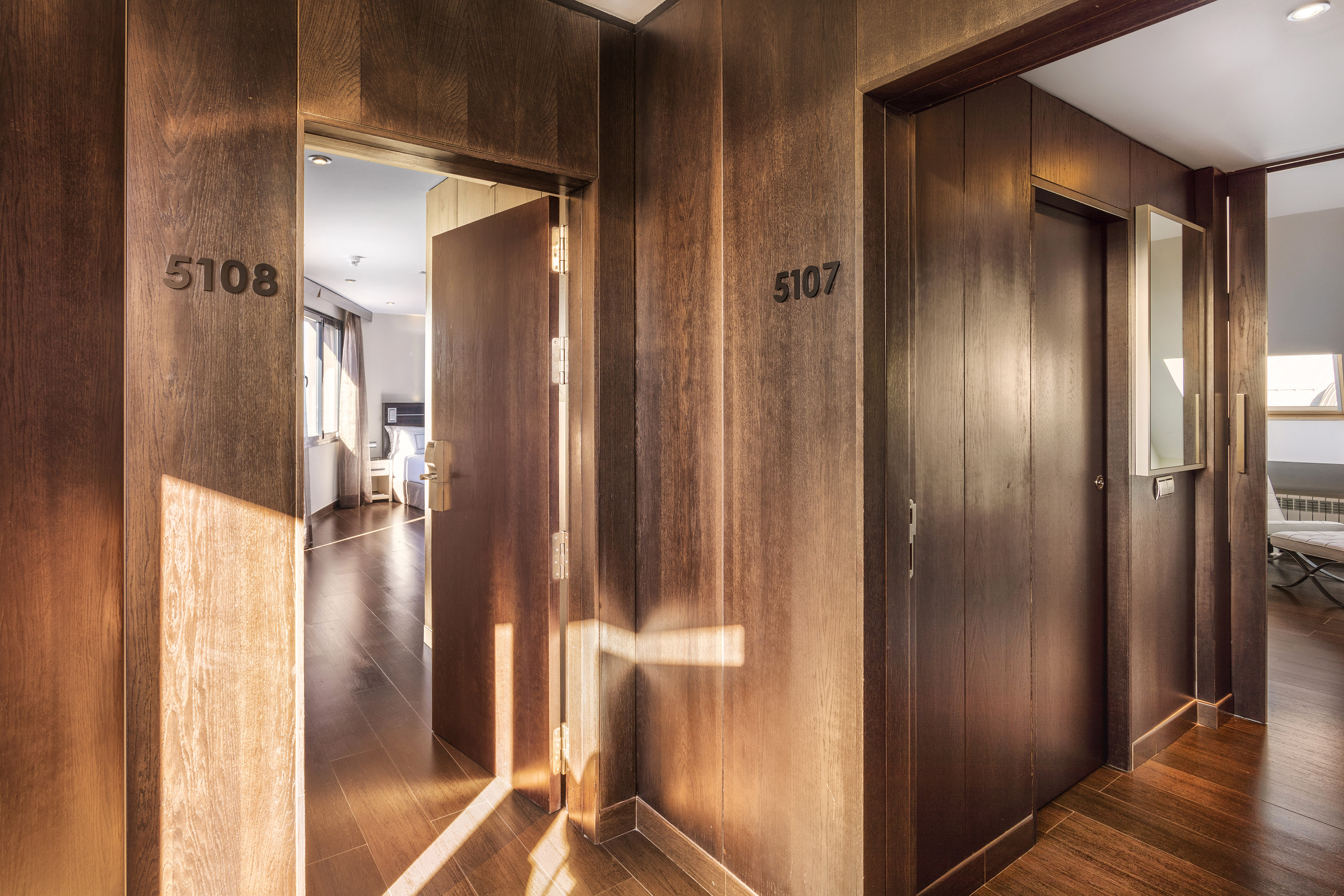 Modern hotel hallway with dark wood paneling, open door to room 5108, door 5107.