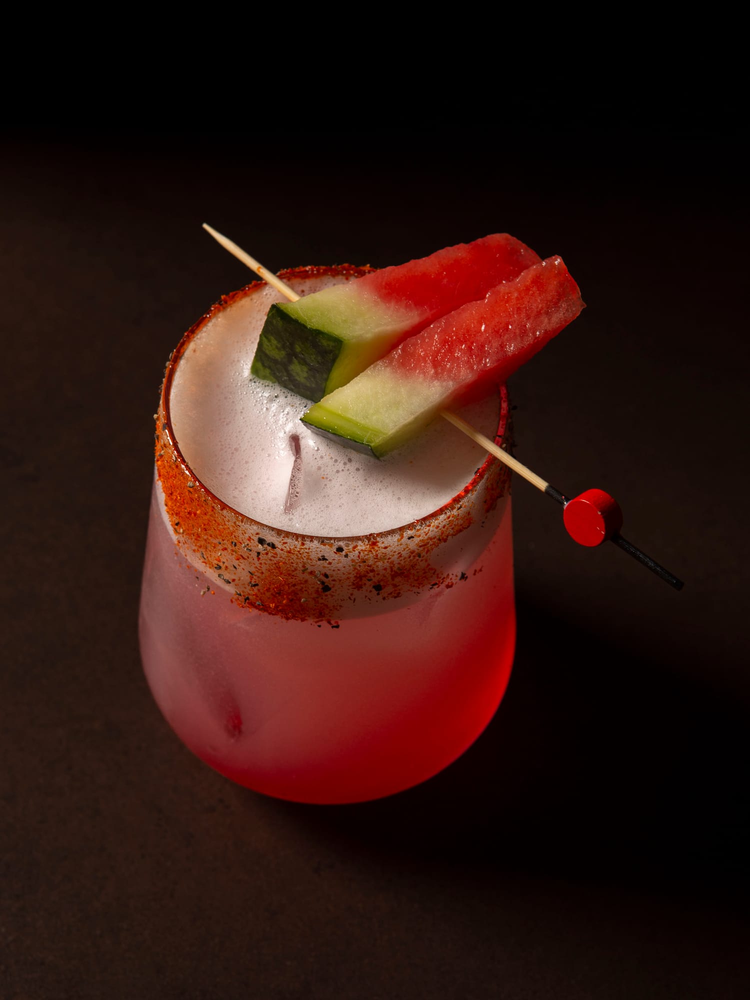 Foamy pink watermelon cocktail with chili-spiced rim and melon slices.