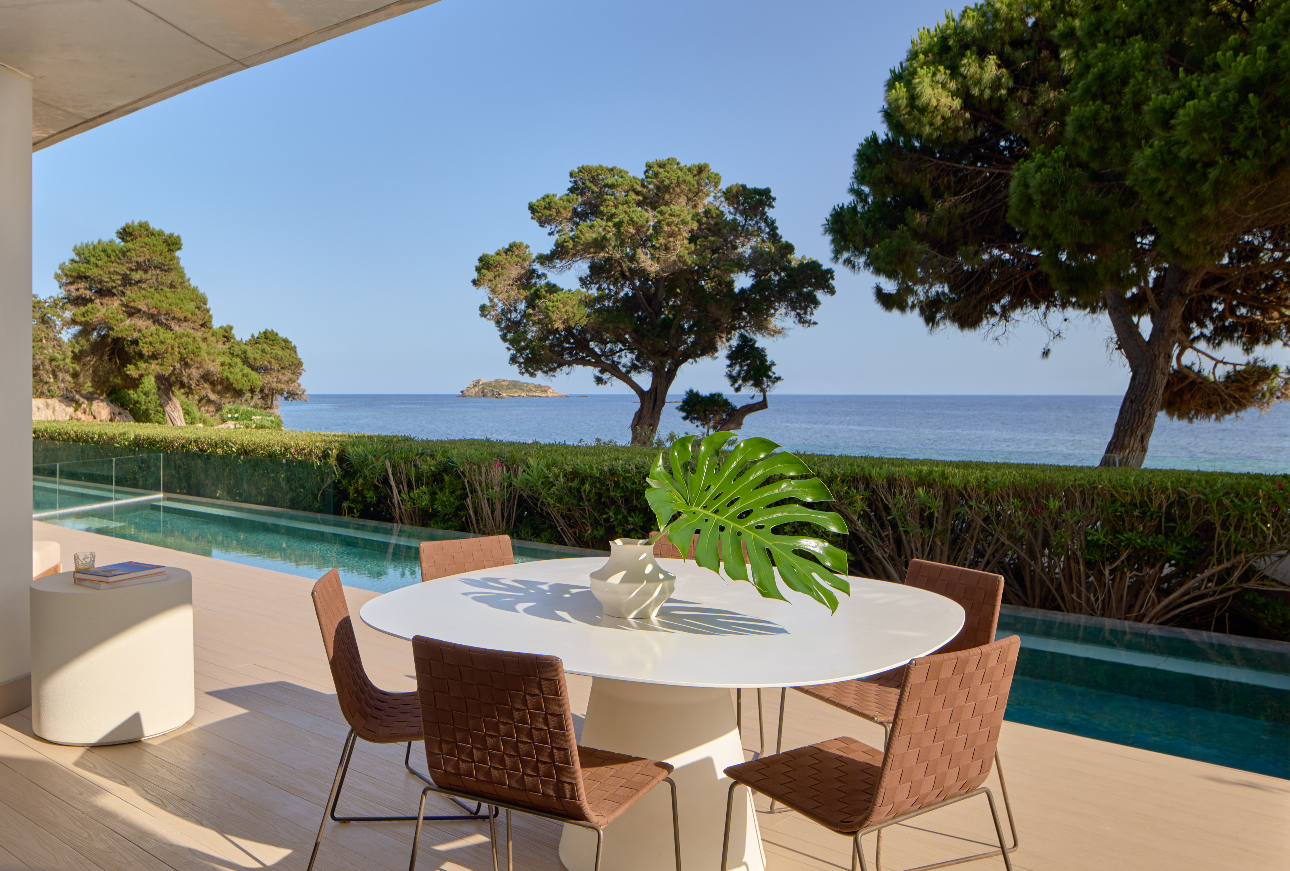 Luxury outdoor patio with modern dining set, infinity pool, and sea view.