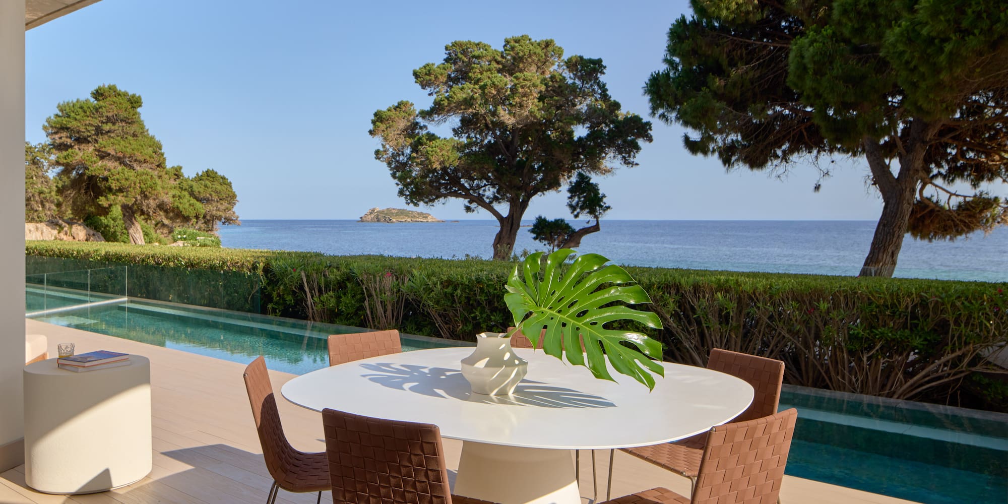 Luxury outdoor patio with modern dining set, infinity pool, and sea view.
