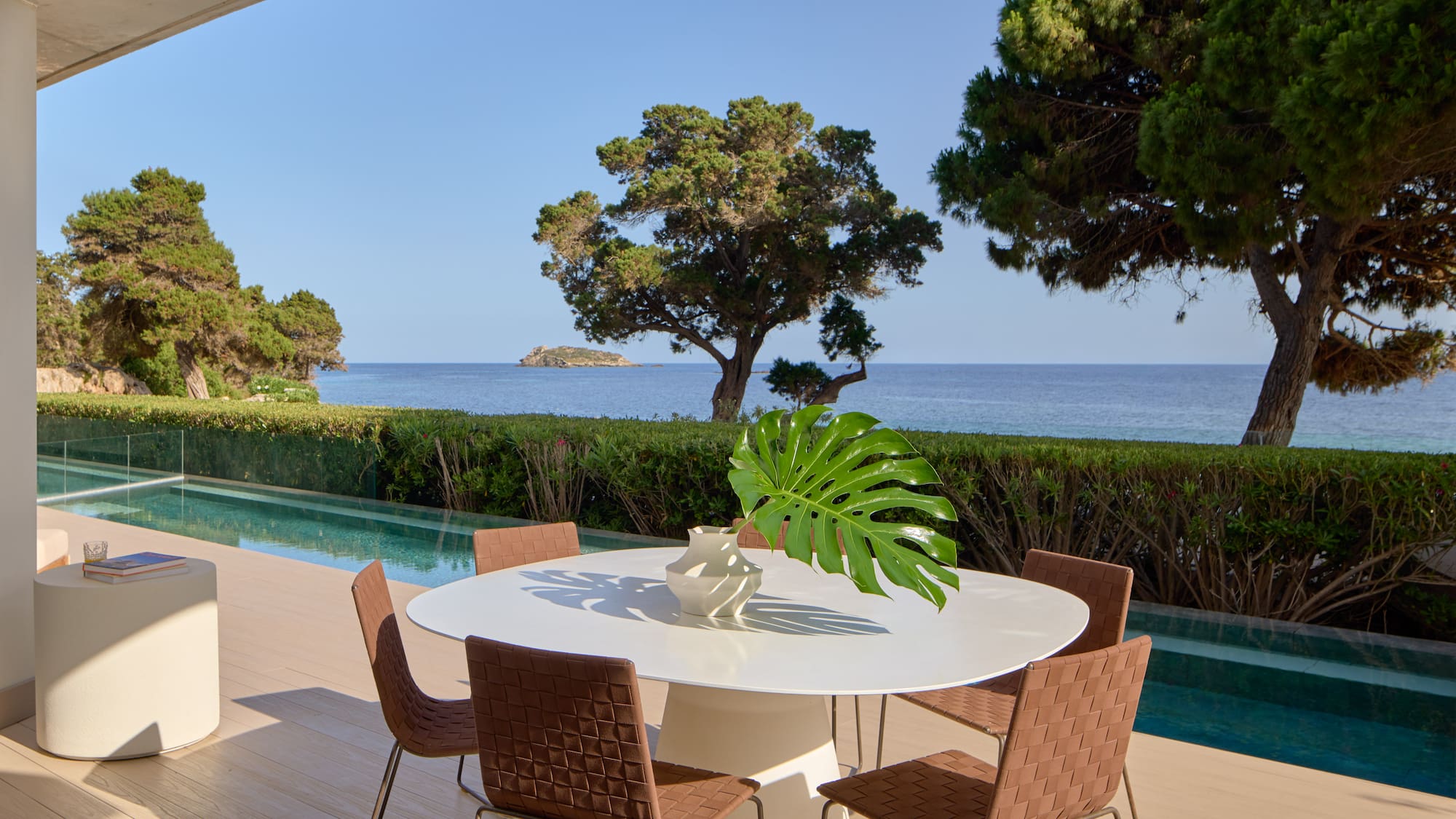 Luxury outdoor patio with modern dining set, infinity pool, and sea view.