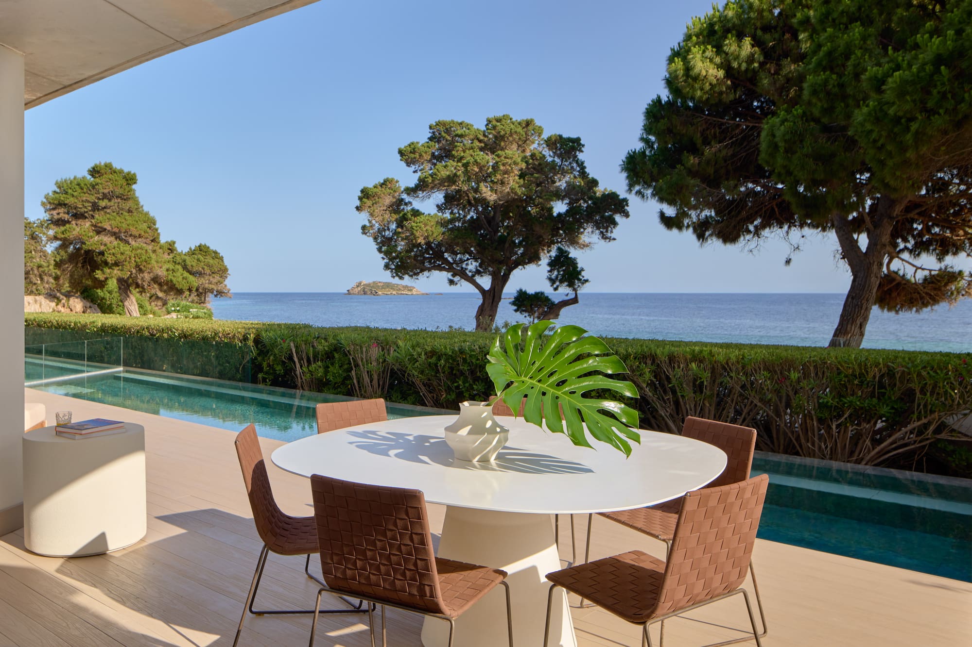 Luxury outdoor patio with modern dining set, infinity pool, and sea view.