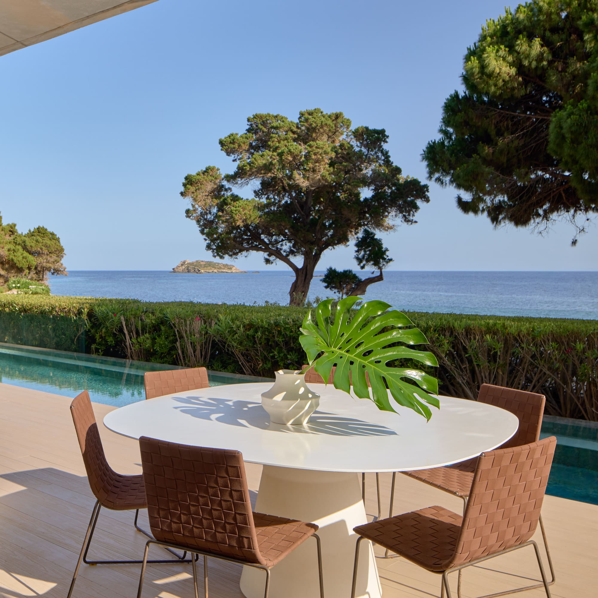 Luxury outdoor patio with modern dining set, infinity pool, and sea view.