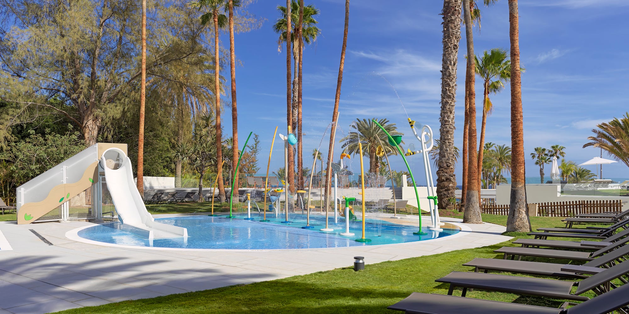 a pool with water slides and chairs and trees
