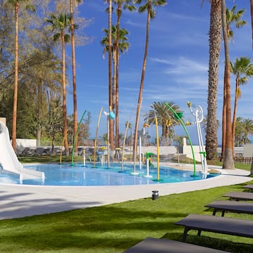 a pool with water slides and chairs and trees