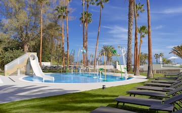 a pool with water slides and chairs and trees