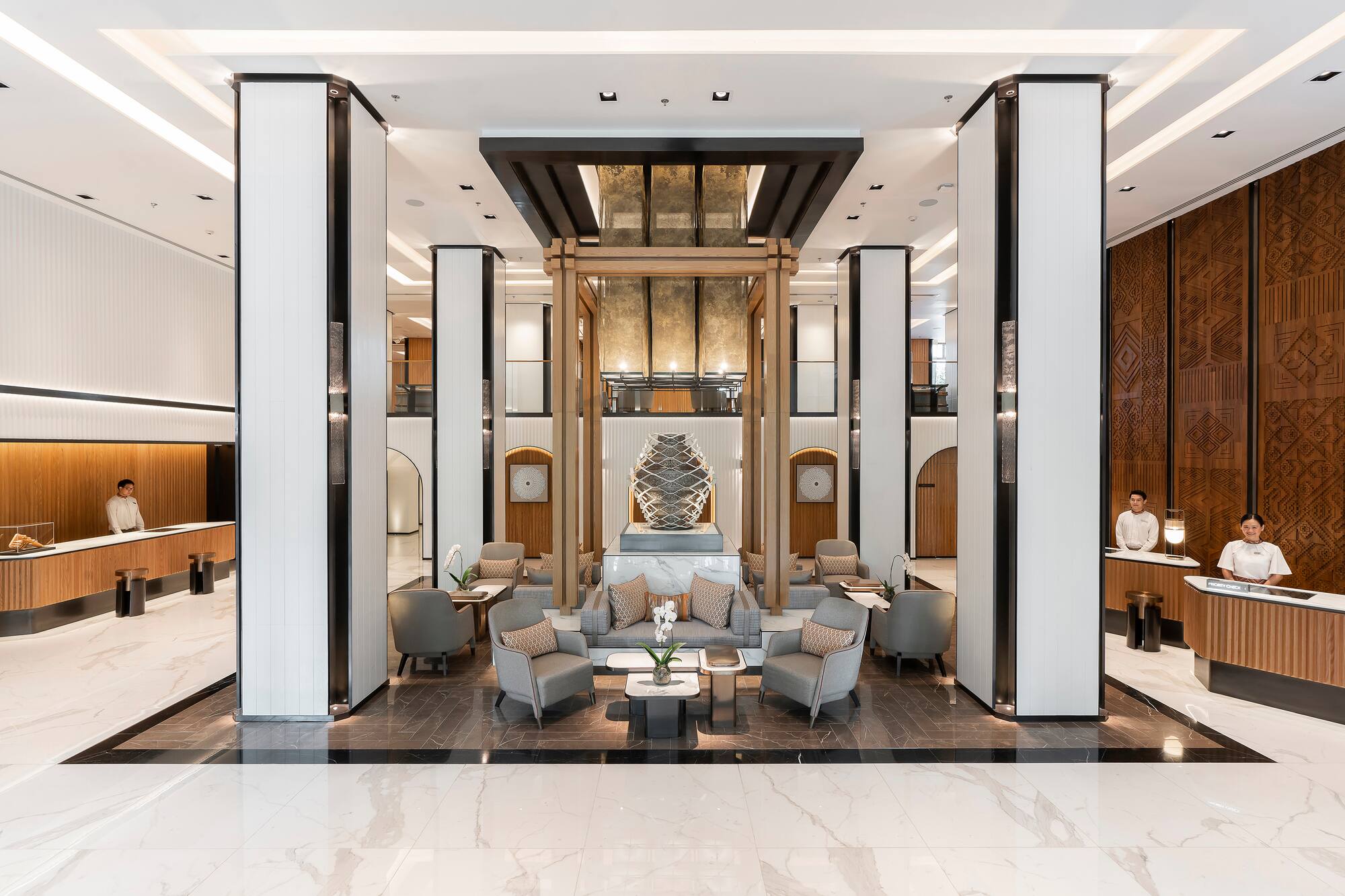 Modern luxury hotel lobby with sculptural centerpiece, reception, lounge.