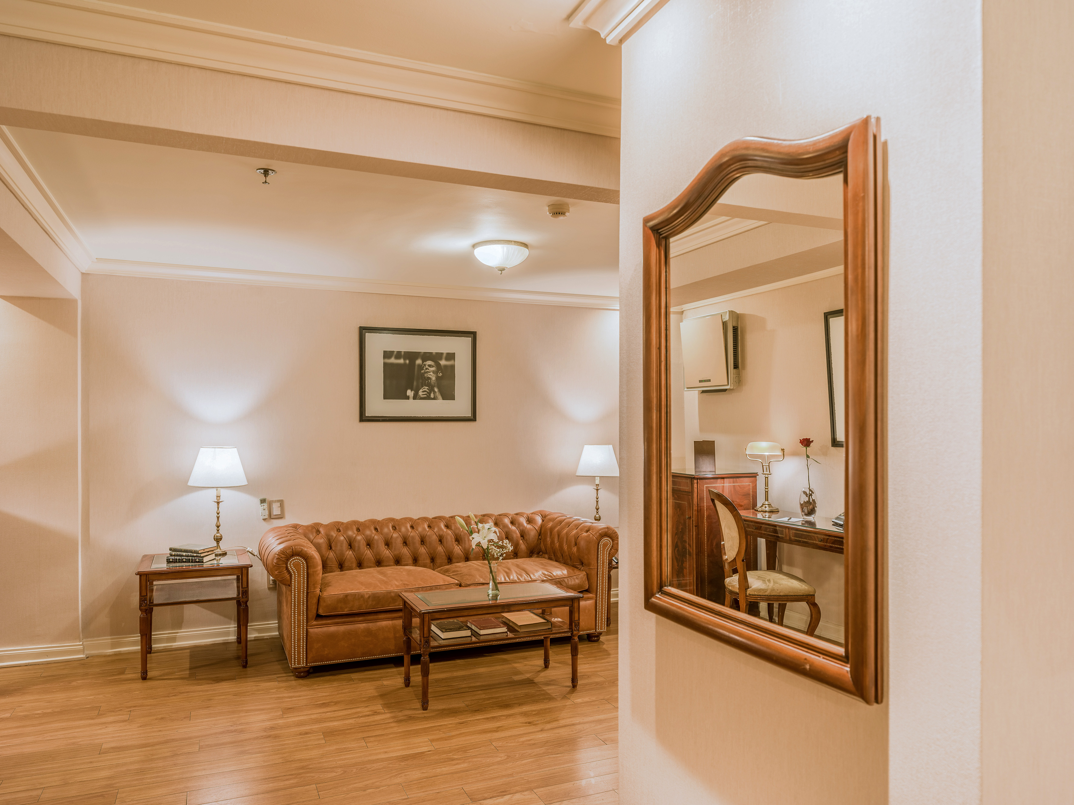 Classic hotel lounge with brown tufted leather sofa, coffee table, and elegant wood decor.