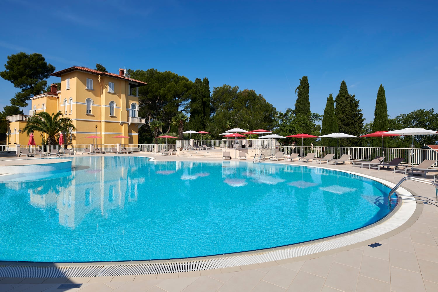 a pool with umbrellas and chairs in front of a building