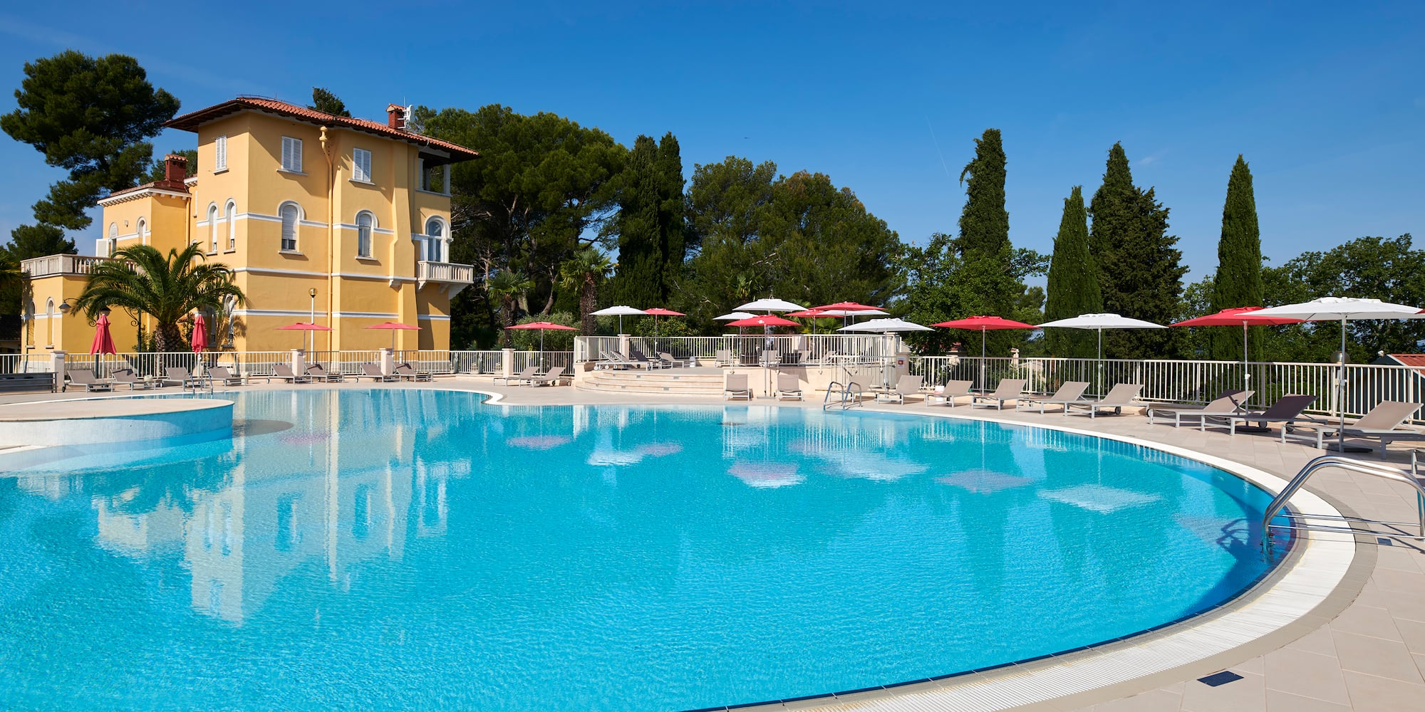 a pool with umbrellas and chairs in front of a building