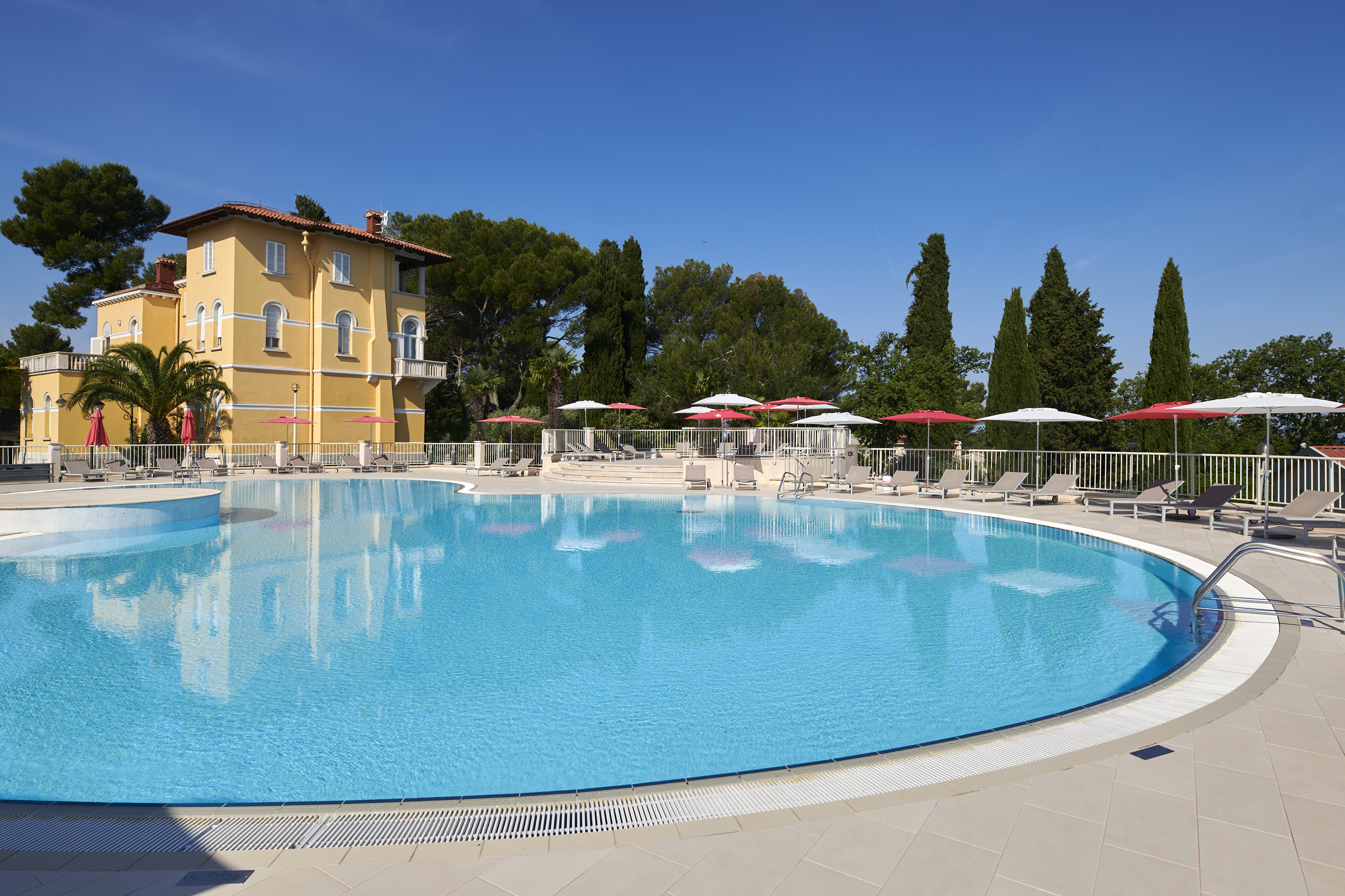 a pool with umbrellas and chairs in front of a building