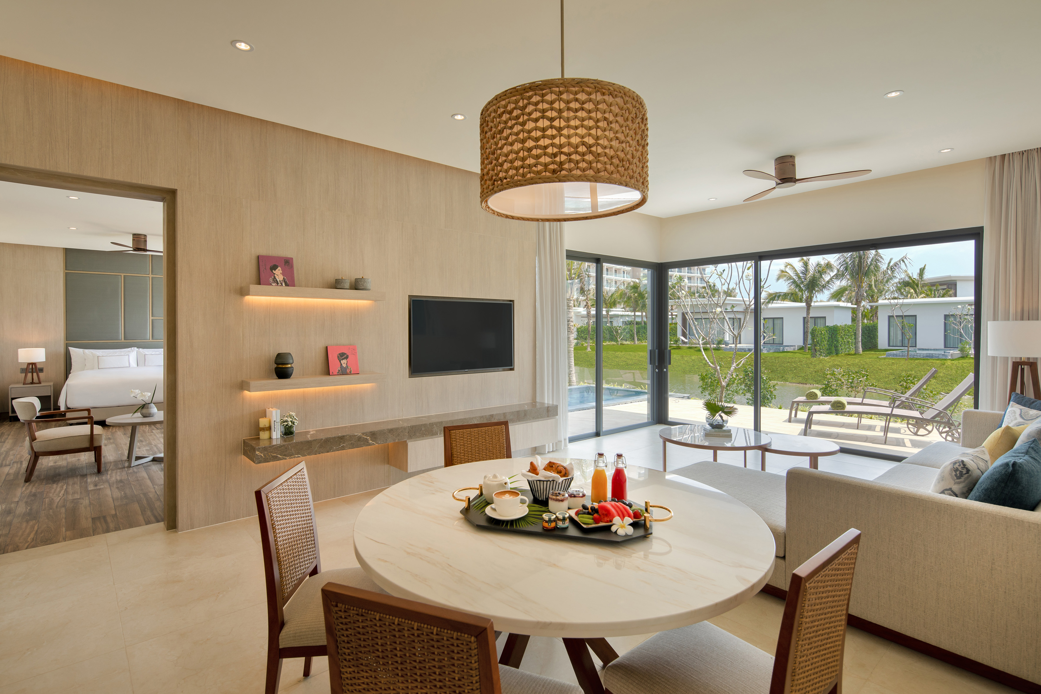 Modern villa living room with breakfast on dining table and tropical pool view.