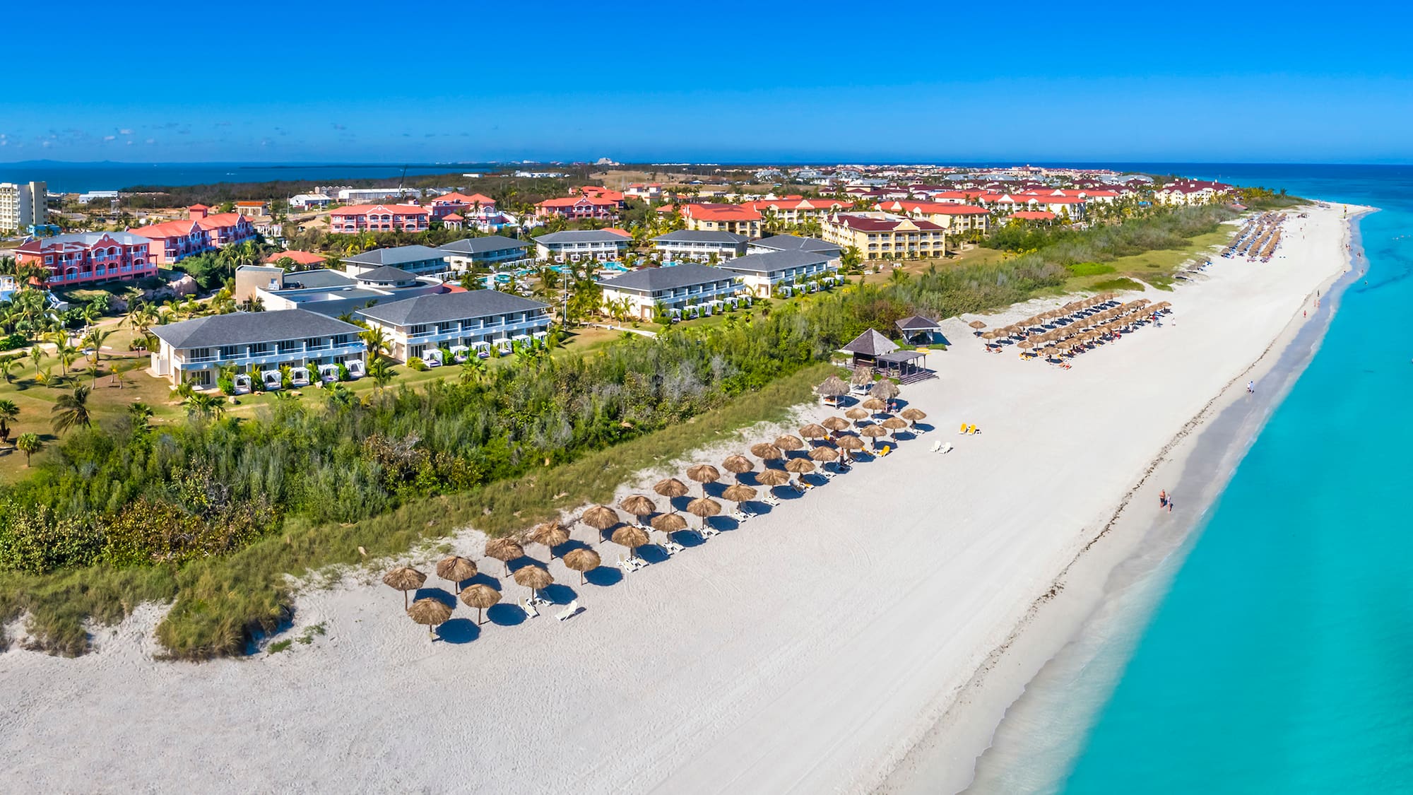a beach with a group of buildings and umbrellas
