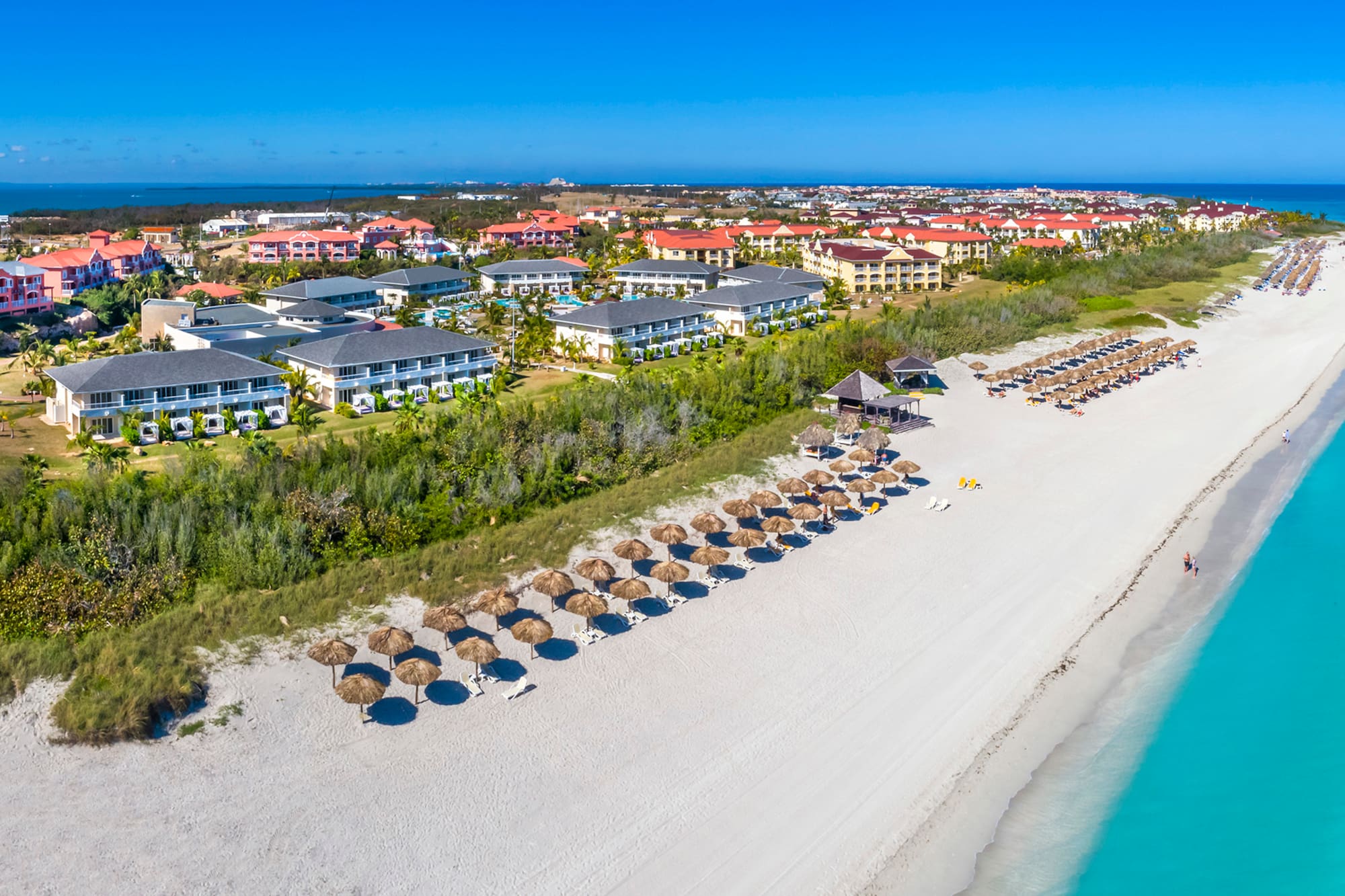 a beach with a group of buildings and umbrellas
