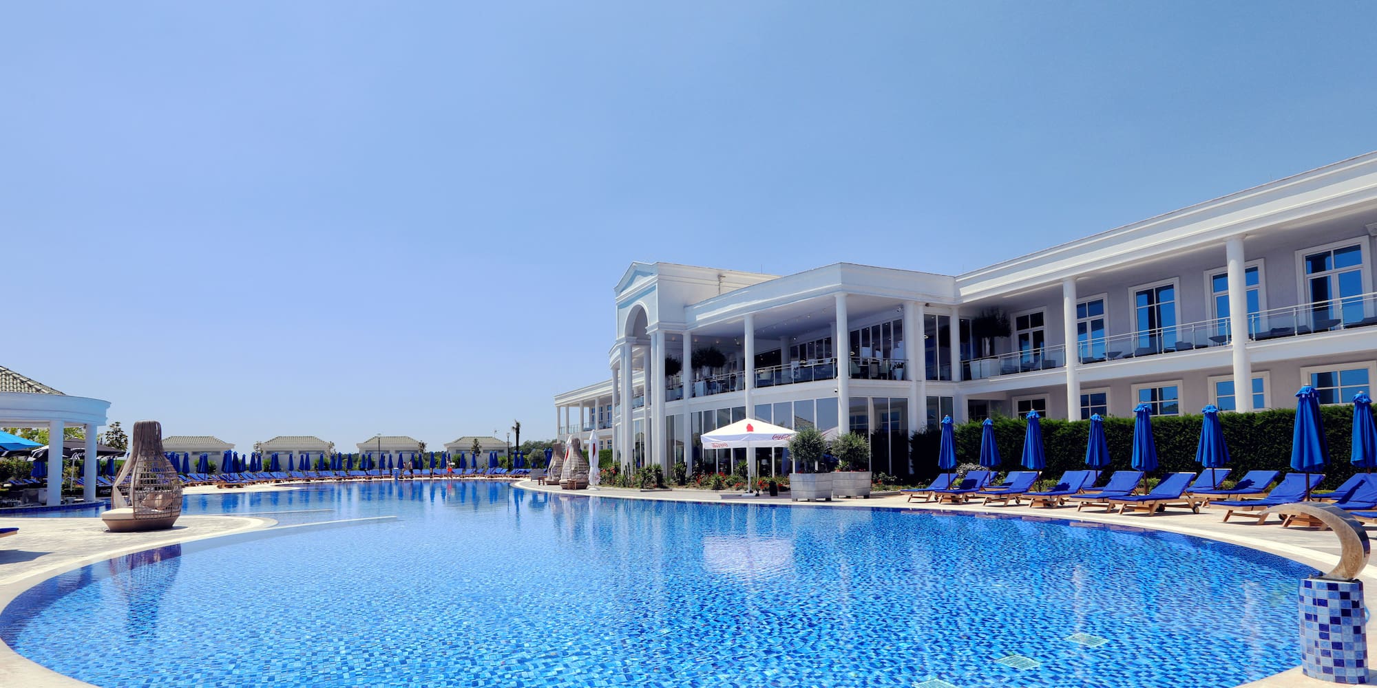 a pool with chairs and umbrellas in front of a building