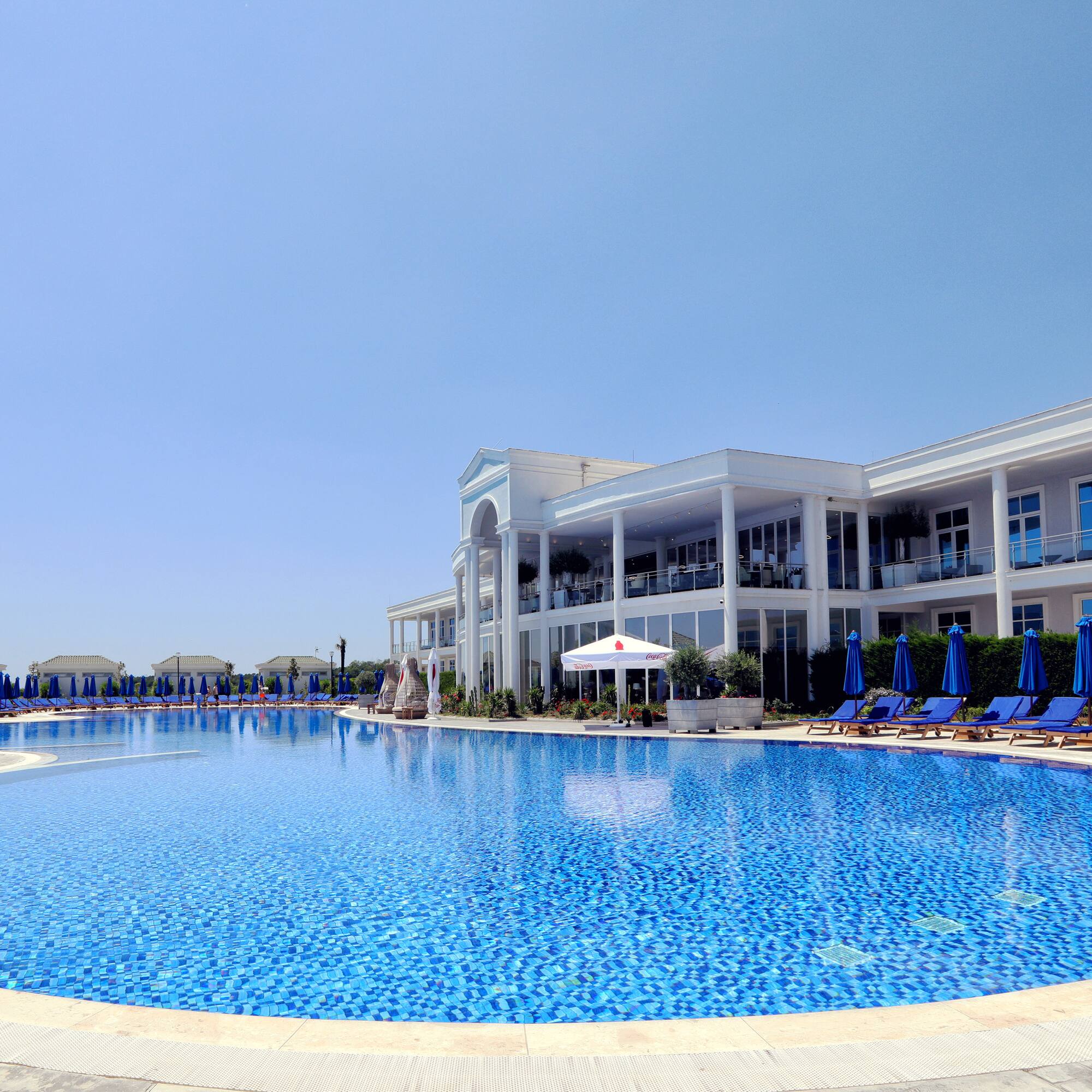 a pool with chairs and umbrellas in front of a building