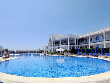 a pool with chairs and umbrellas in front of a building