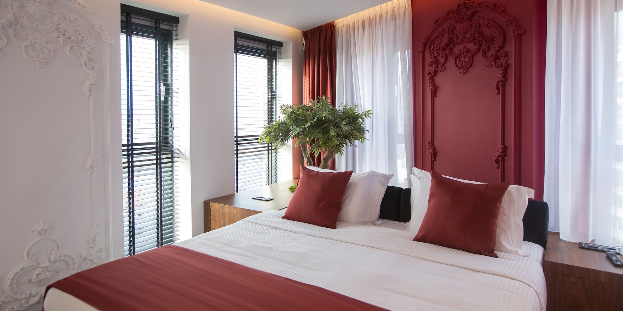 a bed with red pillows and a plant in front of it