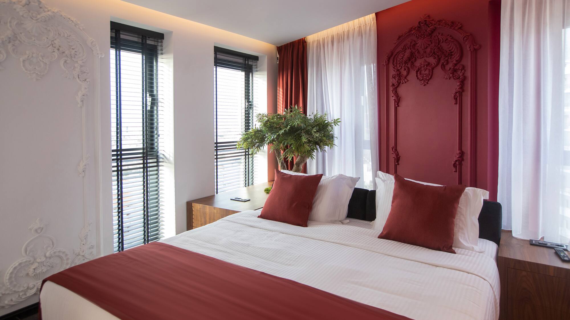 a bed with red pillows and a plant in front of it