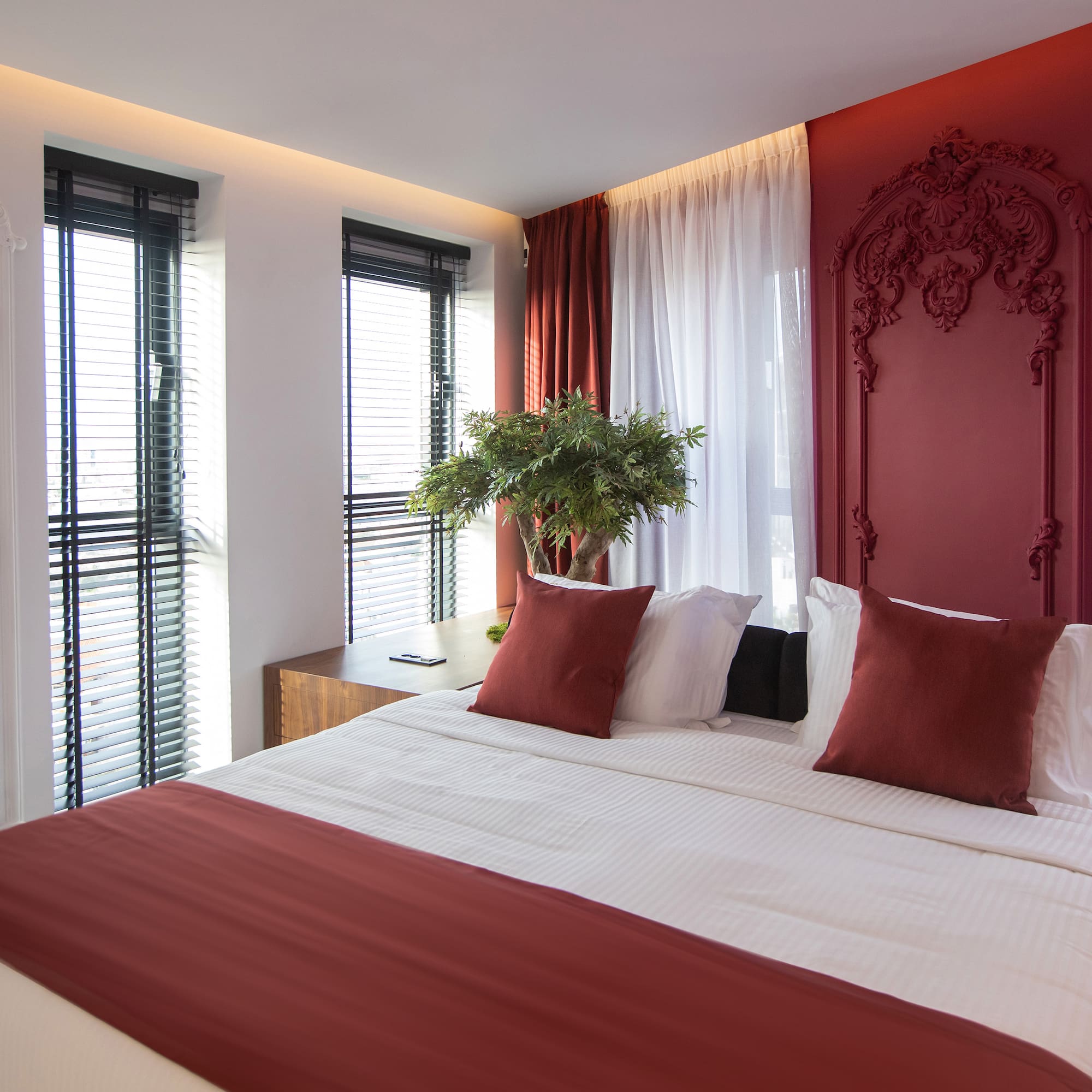 a bed with red pillows and a plant in front of it