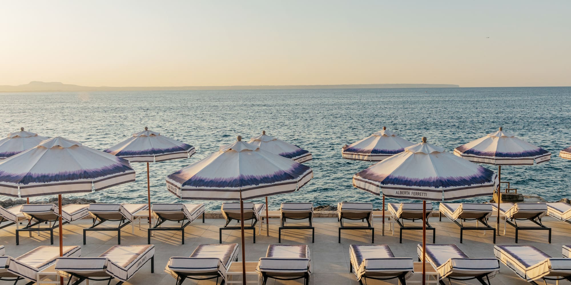 a beach with umbrellas and lounge chairs.