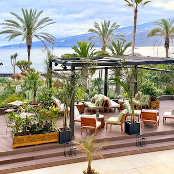 a deck with chairs and trees and water in the background